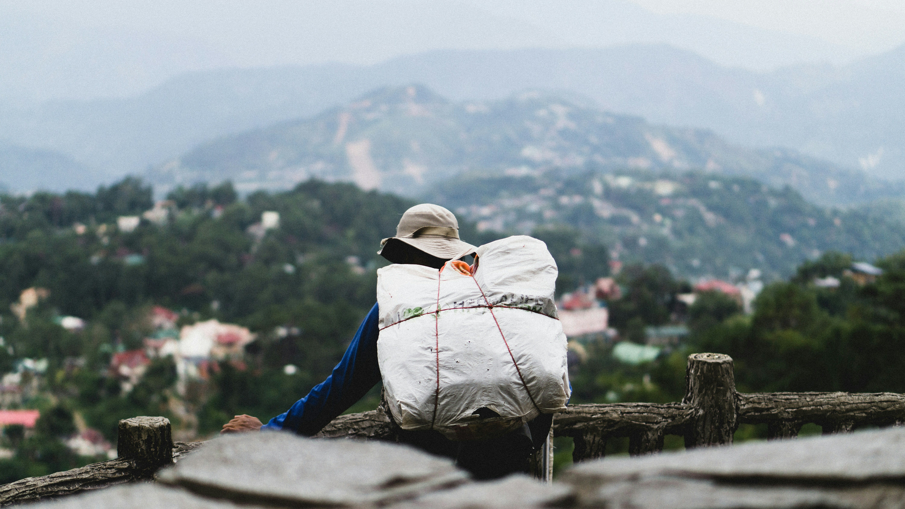 Auto-generated description: A person with a large backpack looks out over a scenic mountain landscape.