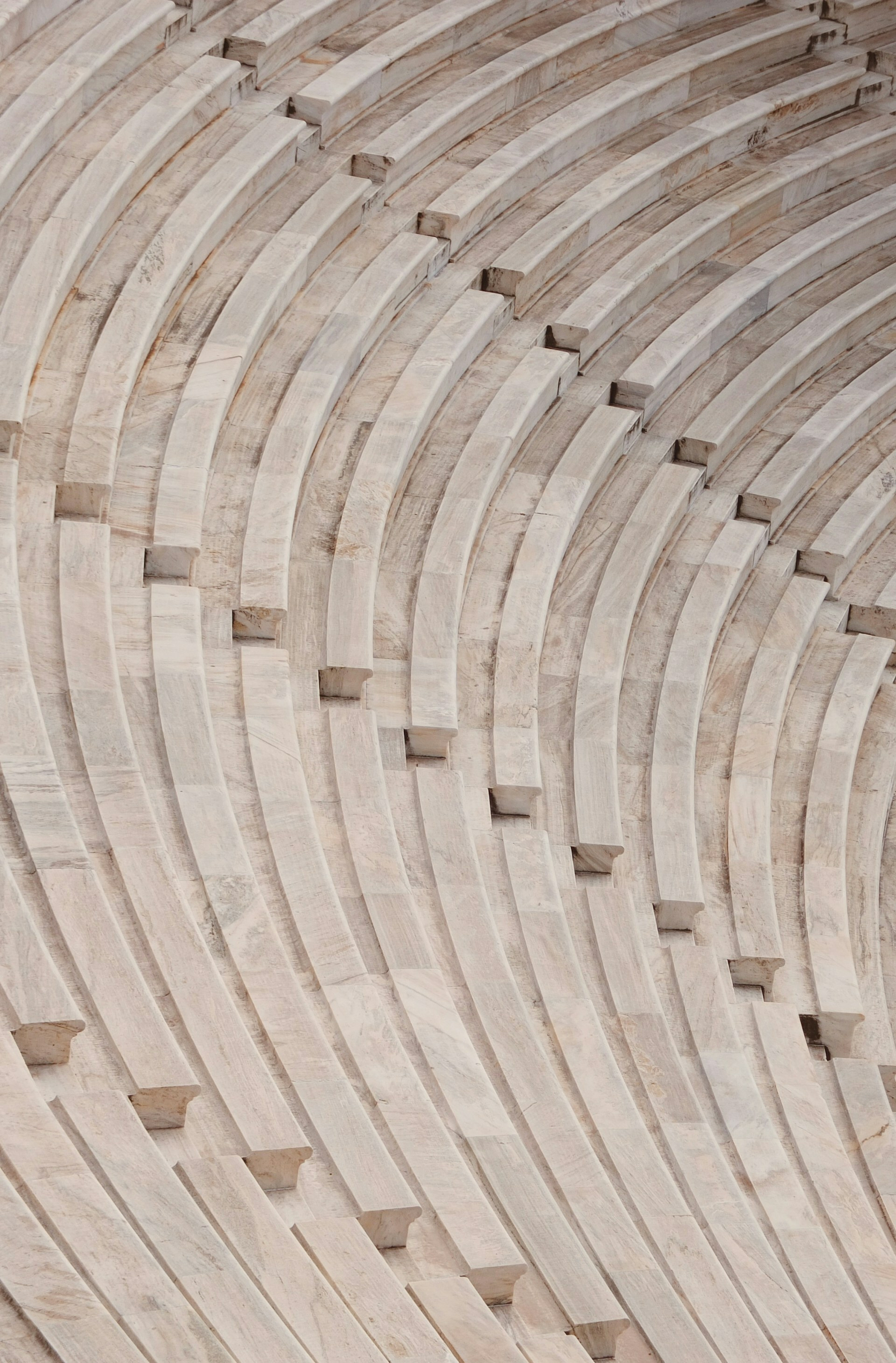 Auto-generated description: Rows of stone seats in an ancient amphitheater create a curved, symmetrical pattern.