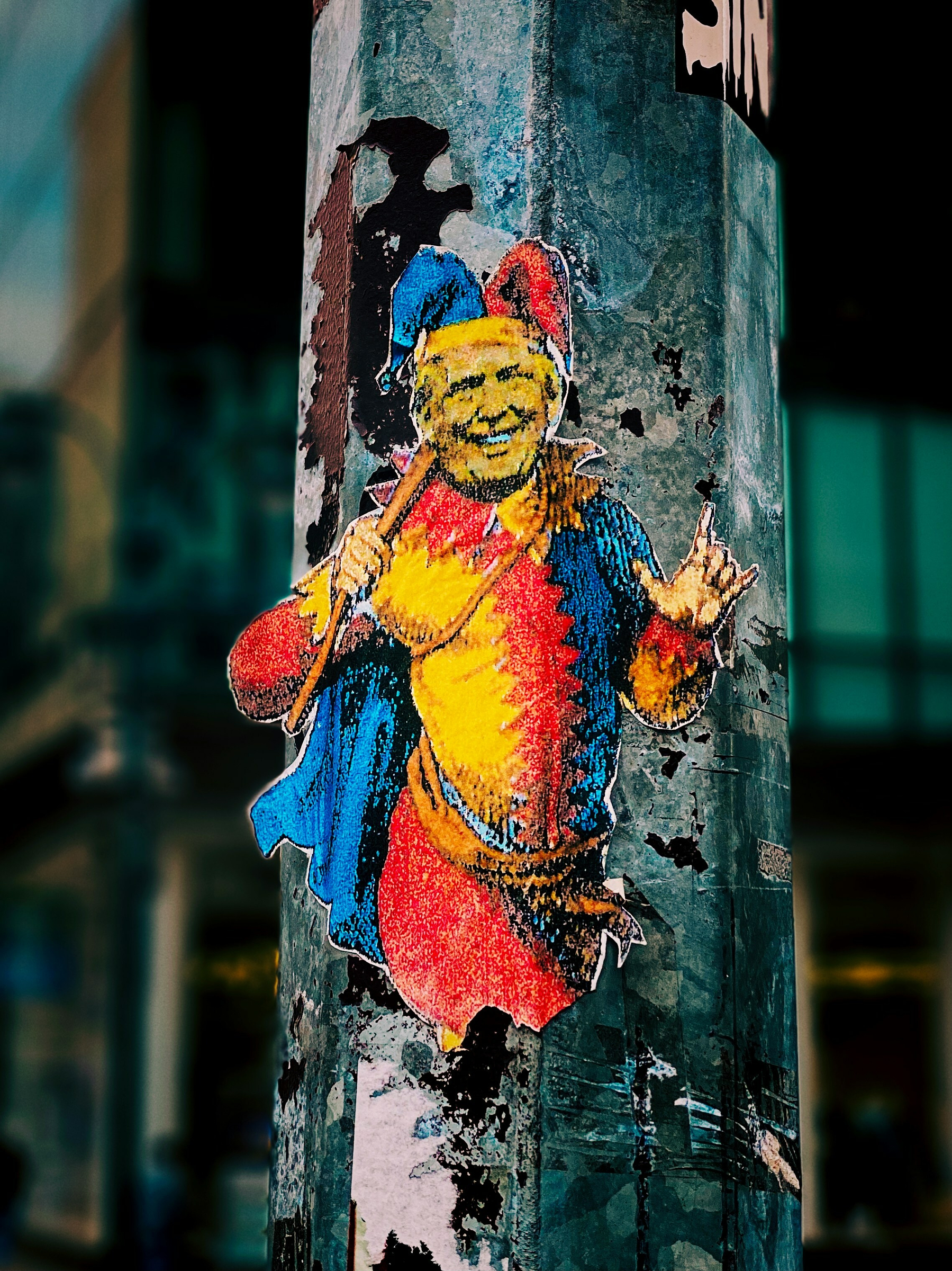 Trump depicted as the Pied Piper on a sticker pasted on a weathered pole in an urban setting.