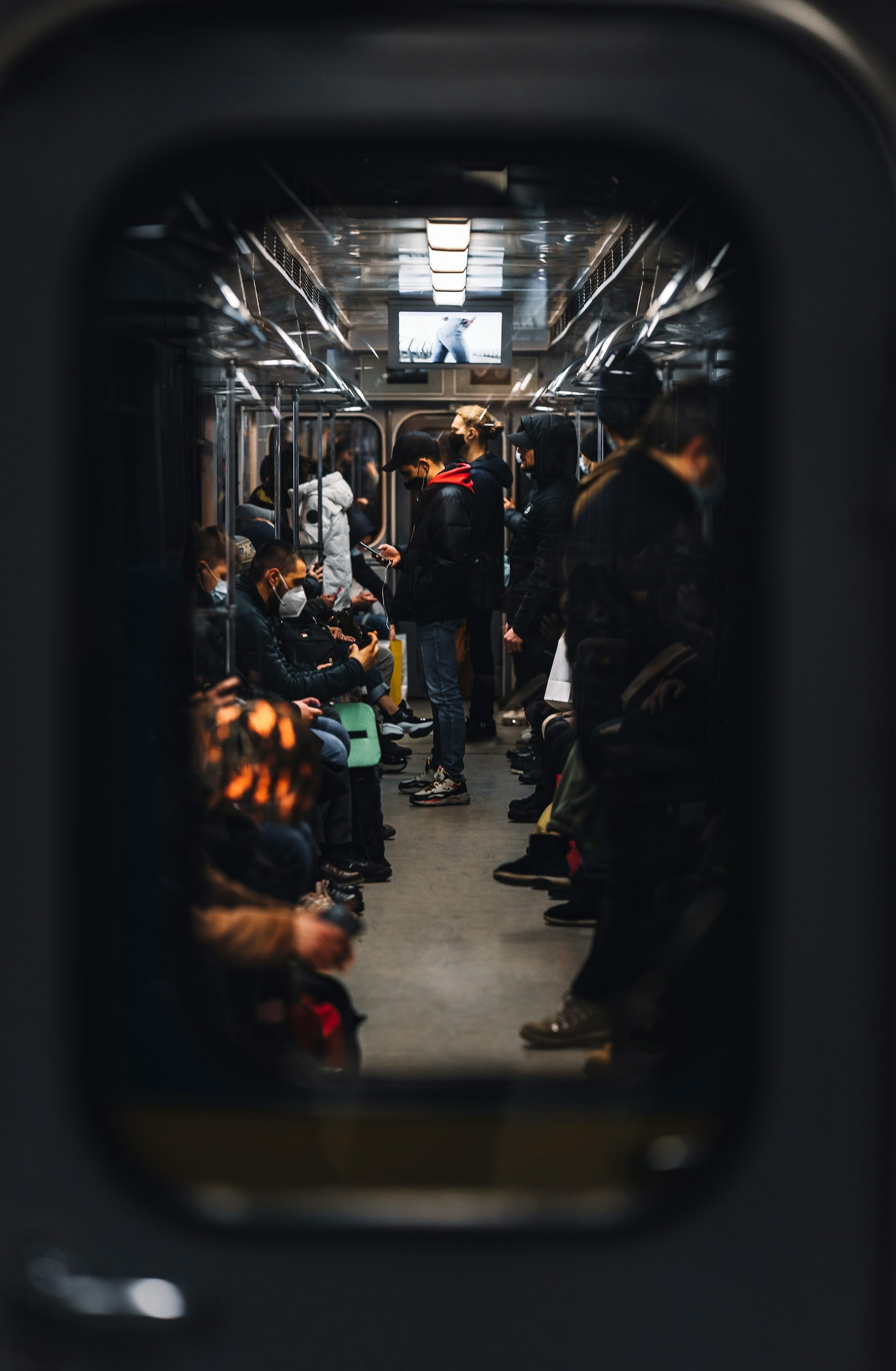 Auto-generated description: Passengers are seated and standing inside a train carriage, viewed through an open doorway.