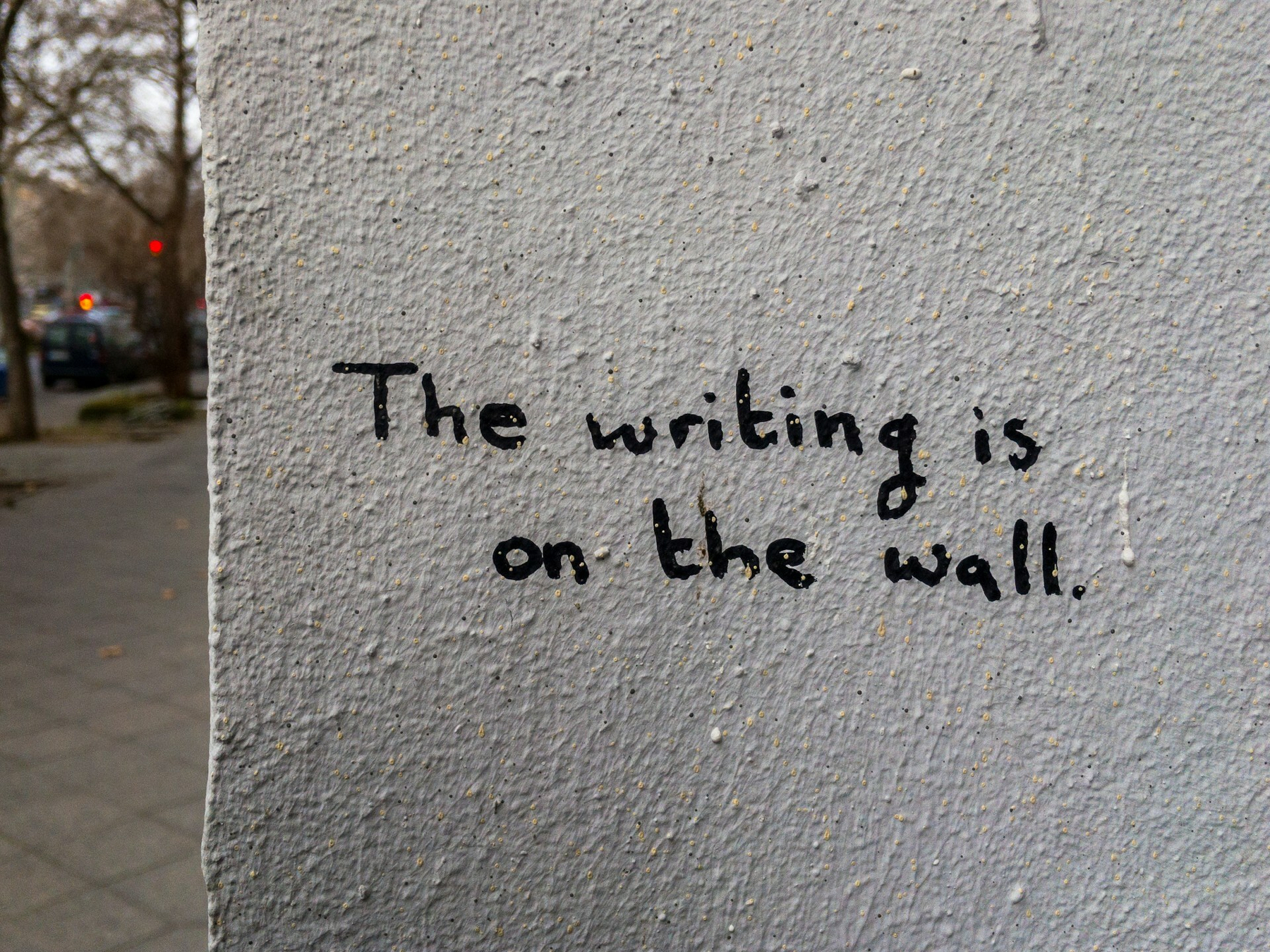 Auto-generated description: A wall contains the handwritten message The writing is on the wall.