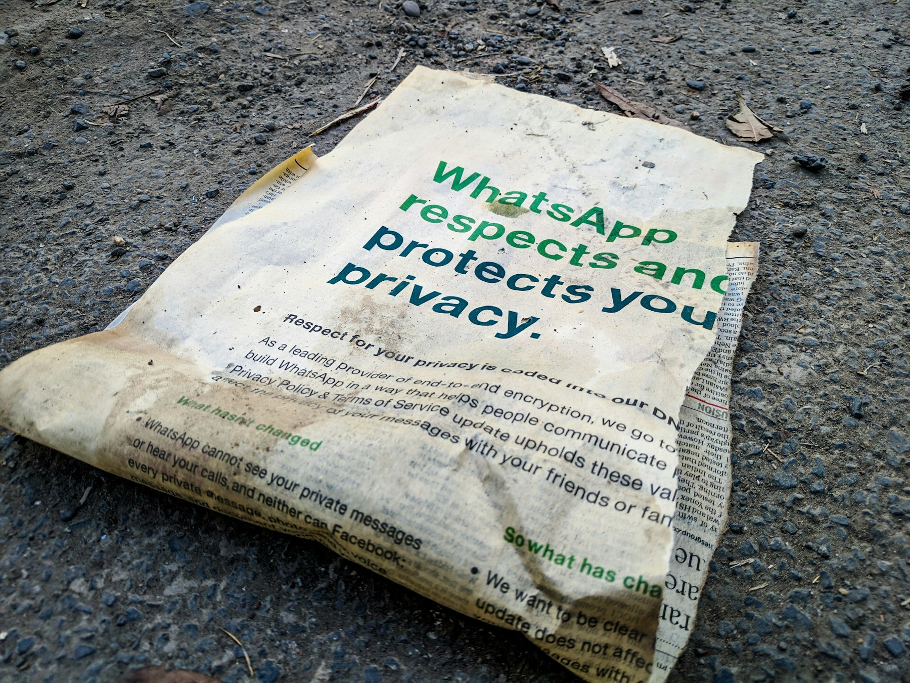 Auto-generated description: A crumpled piece of paper on the ground displays the words WhatsApp respects and protects your privacy.