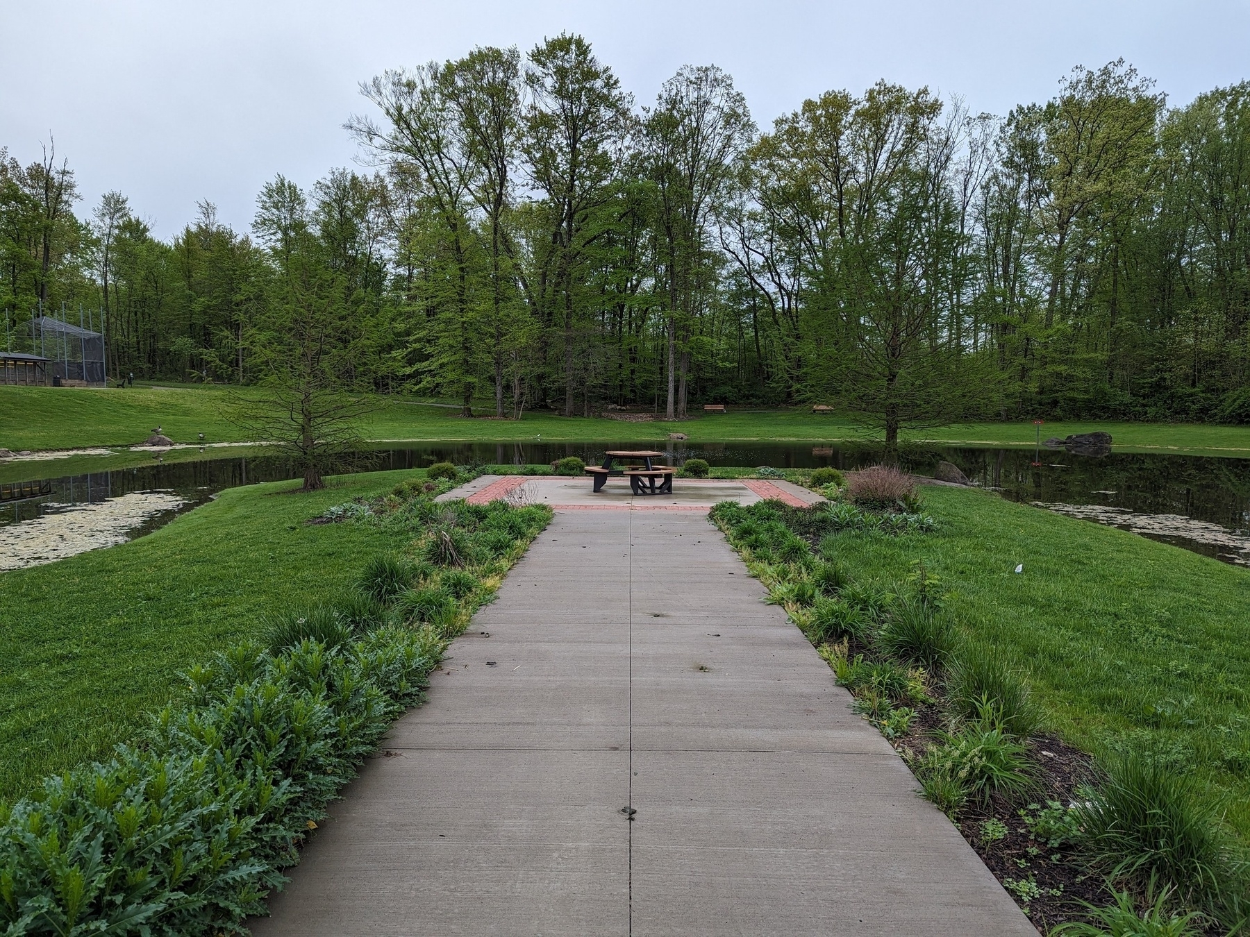 Concrete pathway leading to a picnic table on a peninsula surrounded by water