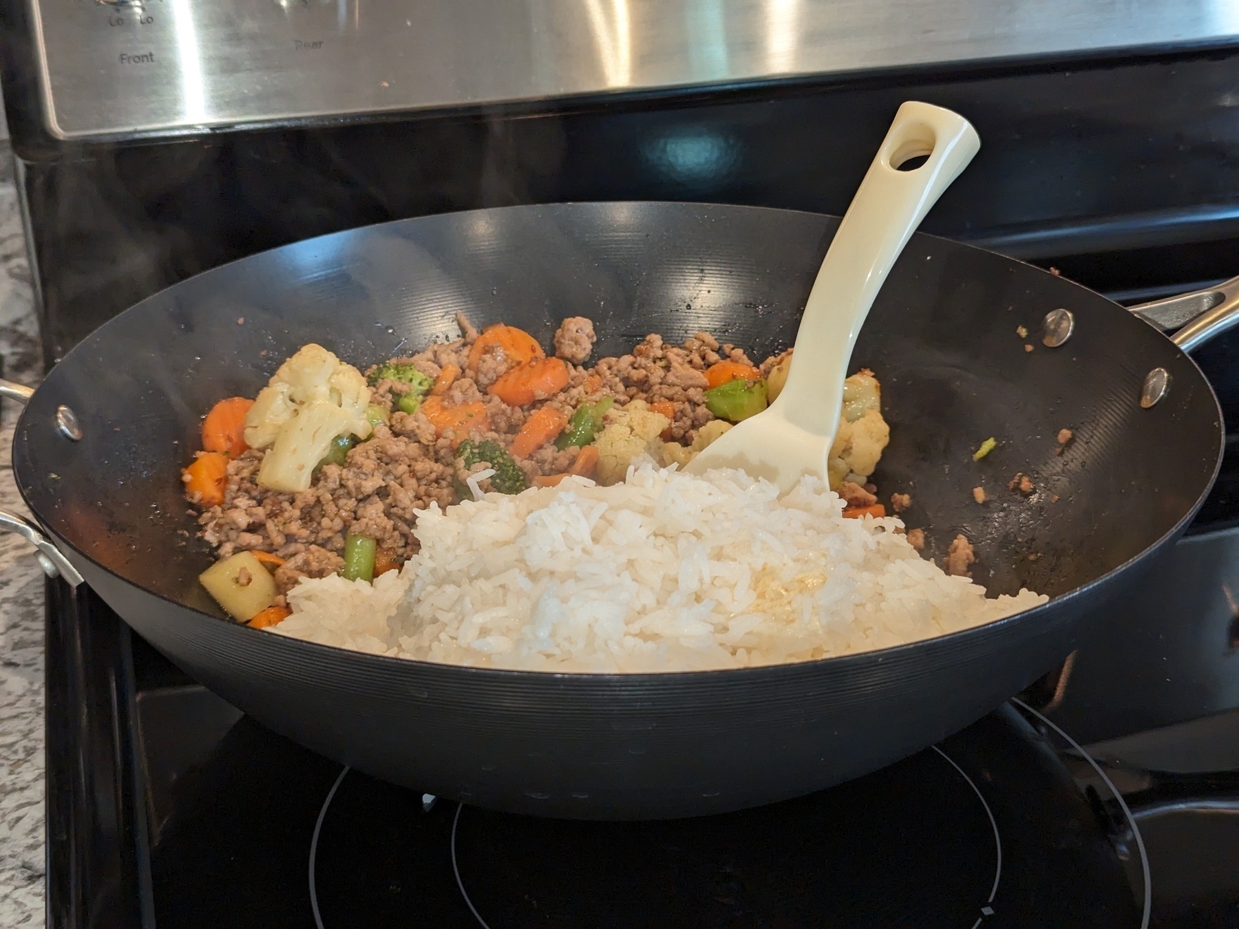 White rice, pork, and mixed vegetables in a wok.