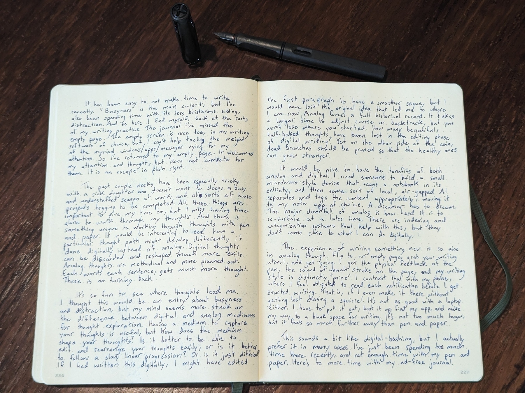 A journal and Lamy Safari fountain pen on a dark stained wood table