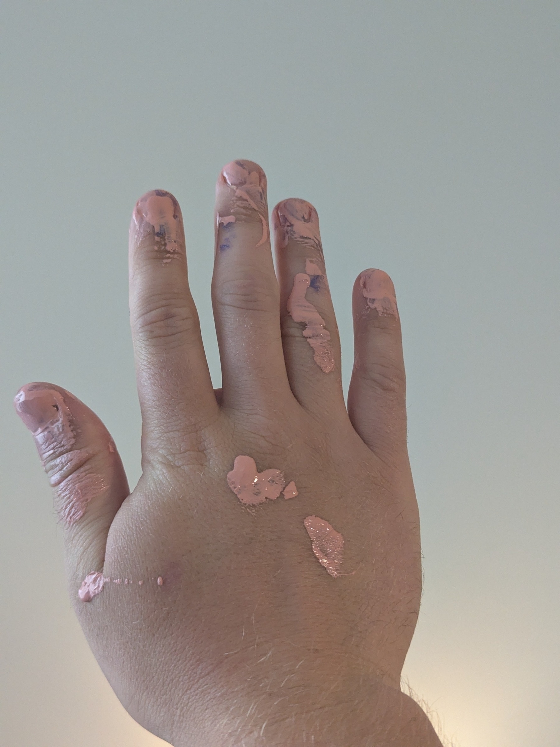 A hand is covered in dried pink paint.