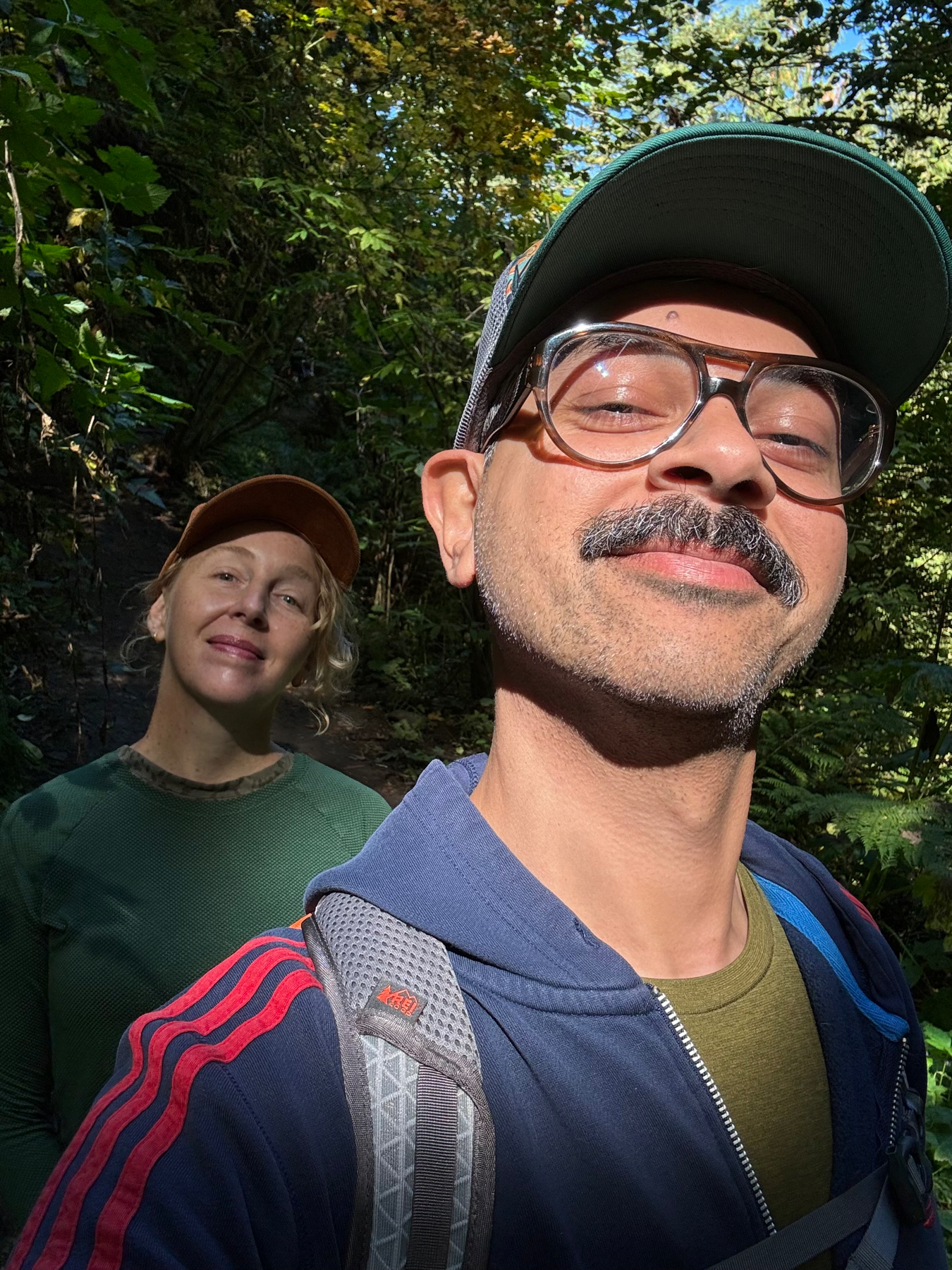 Selfie of two people in a sun speckled forest