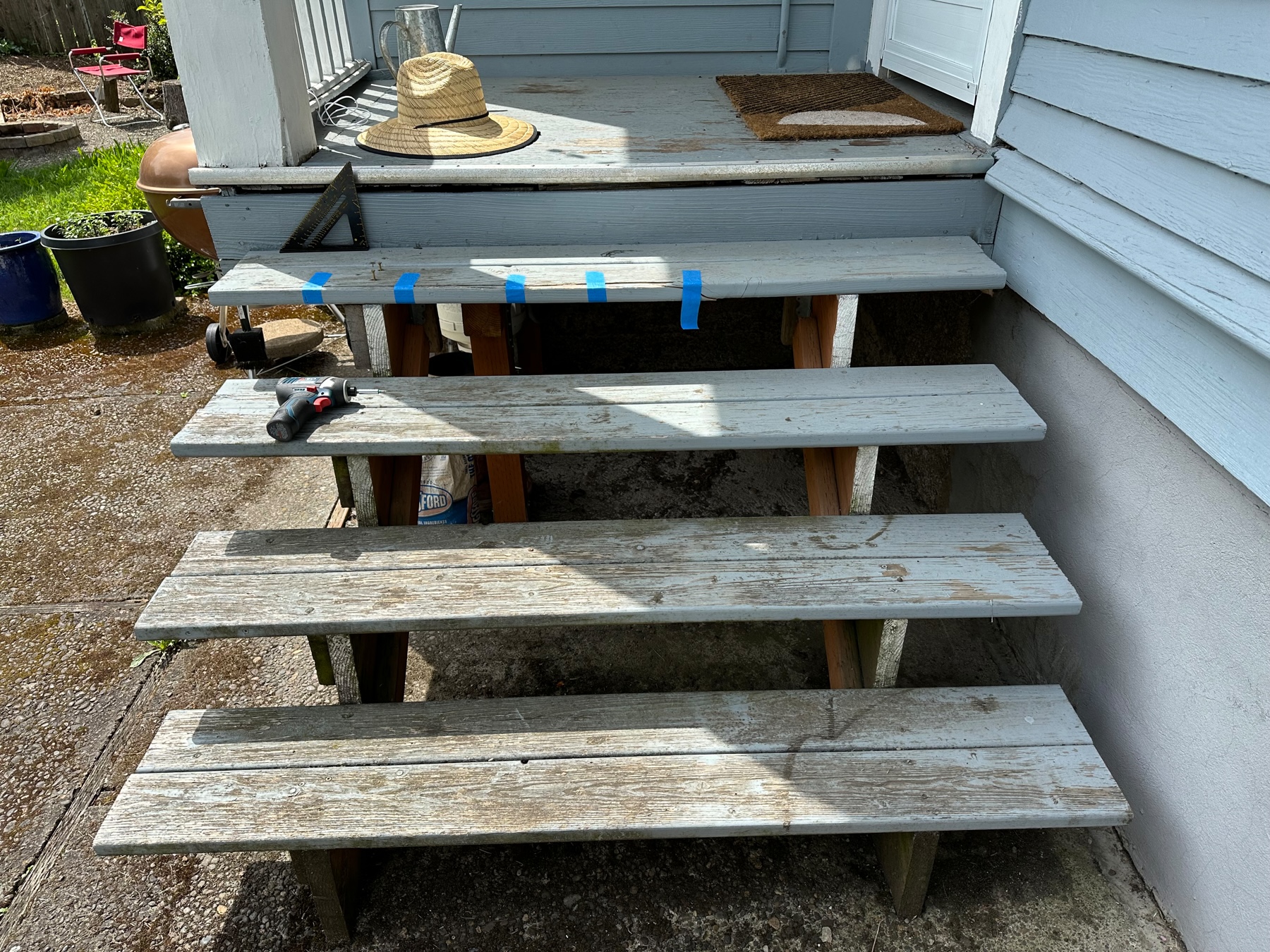 Front view of steps. There’s blue tape on a board on the top tread.