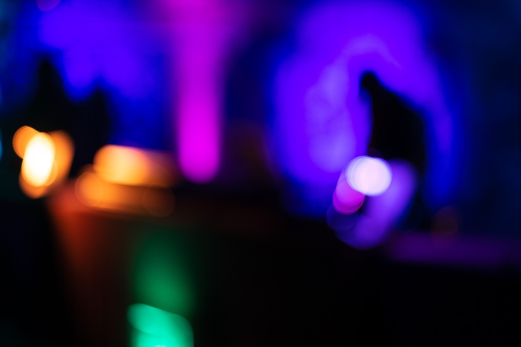 An out of focus image of blurry blobs of color and bokeh on a black background.