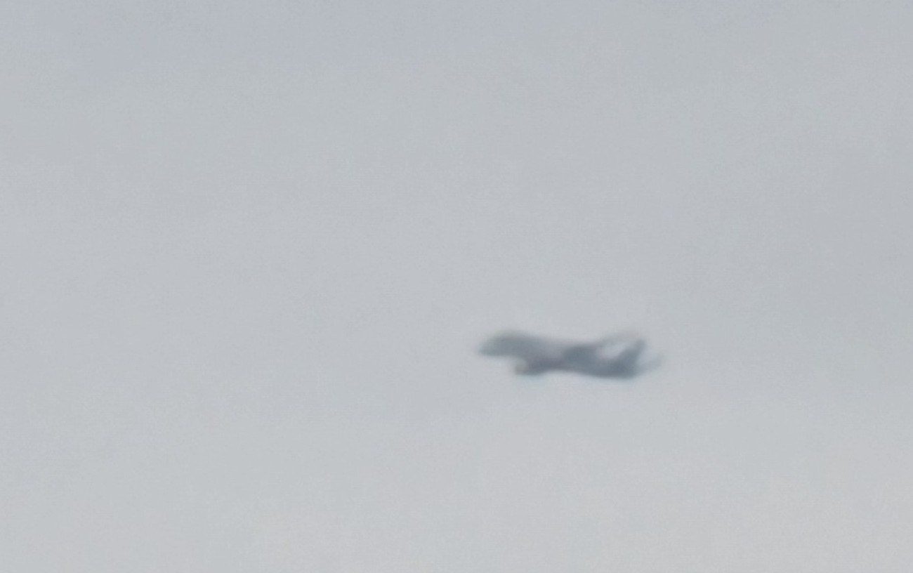 A blurry image of the Beluga plane against a gray sky.