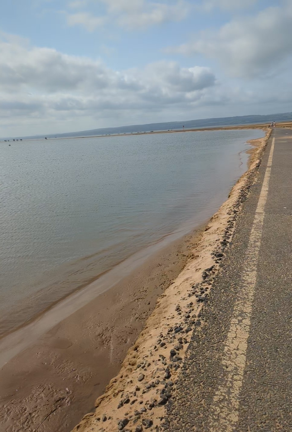 Edge of the marine lake with sandy edge under a partly cloudy sky. 