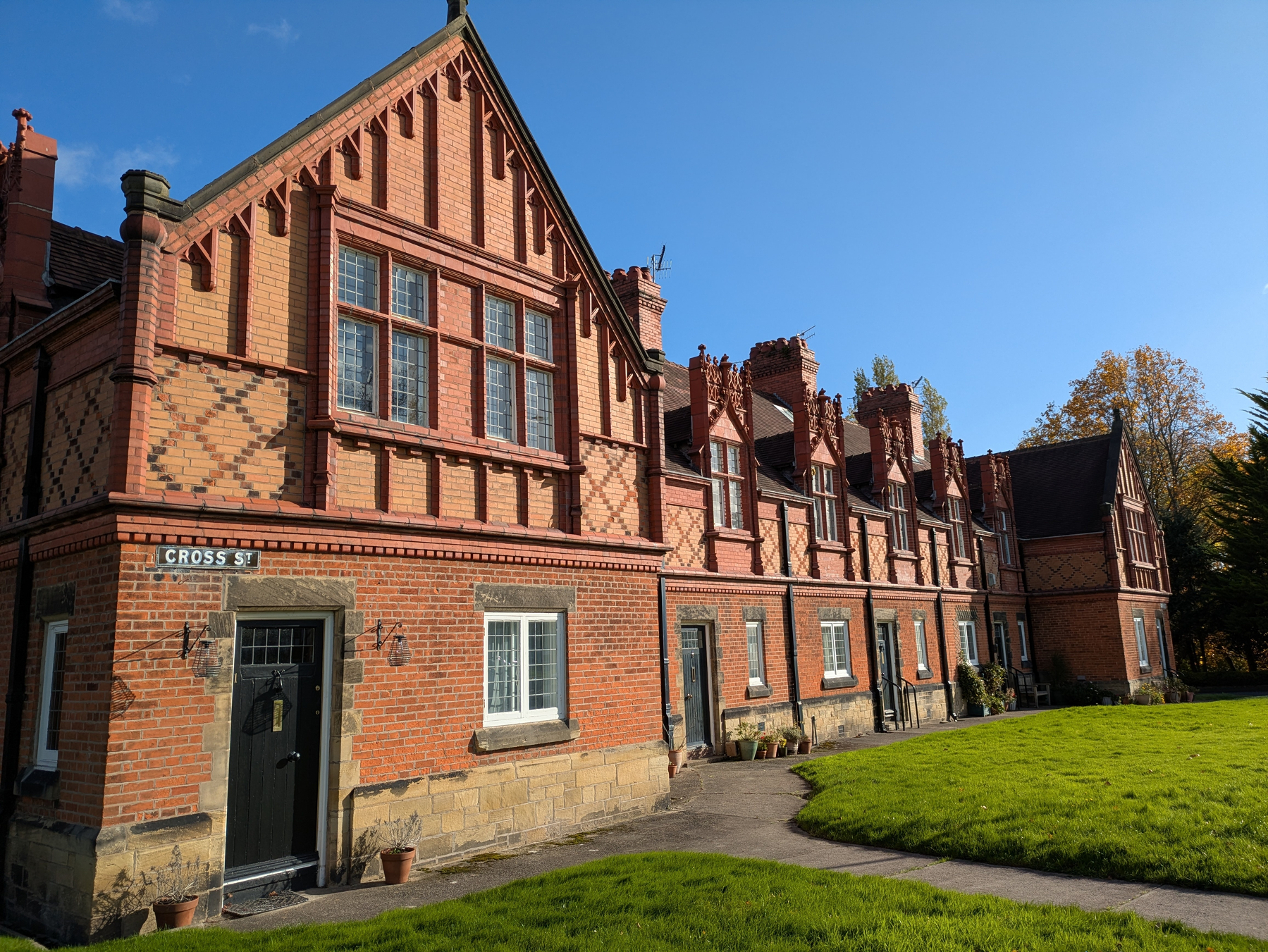 A row of charming, historic brick houses is set against a clear blue sky with a well-maintained lawn in front.