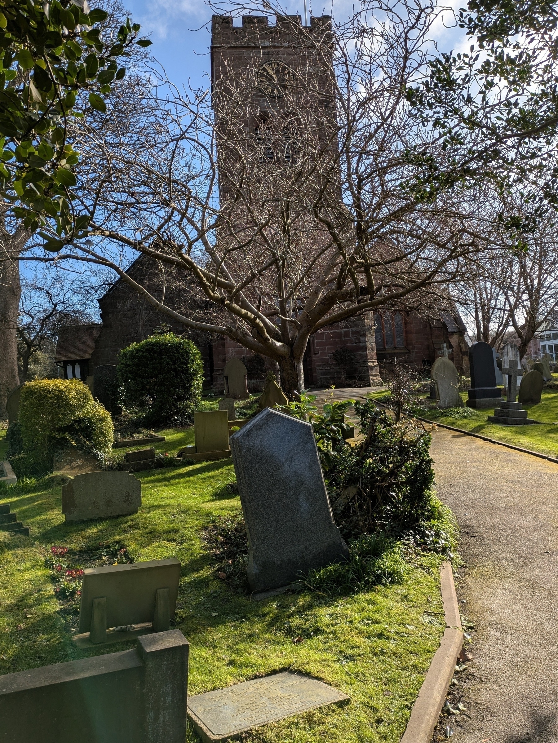 A scenic churchyard features an old church with a tall tower, surrounded by tombstones and lush greenery.