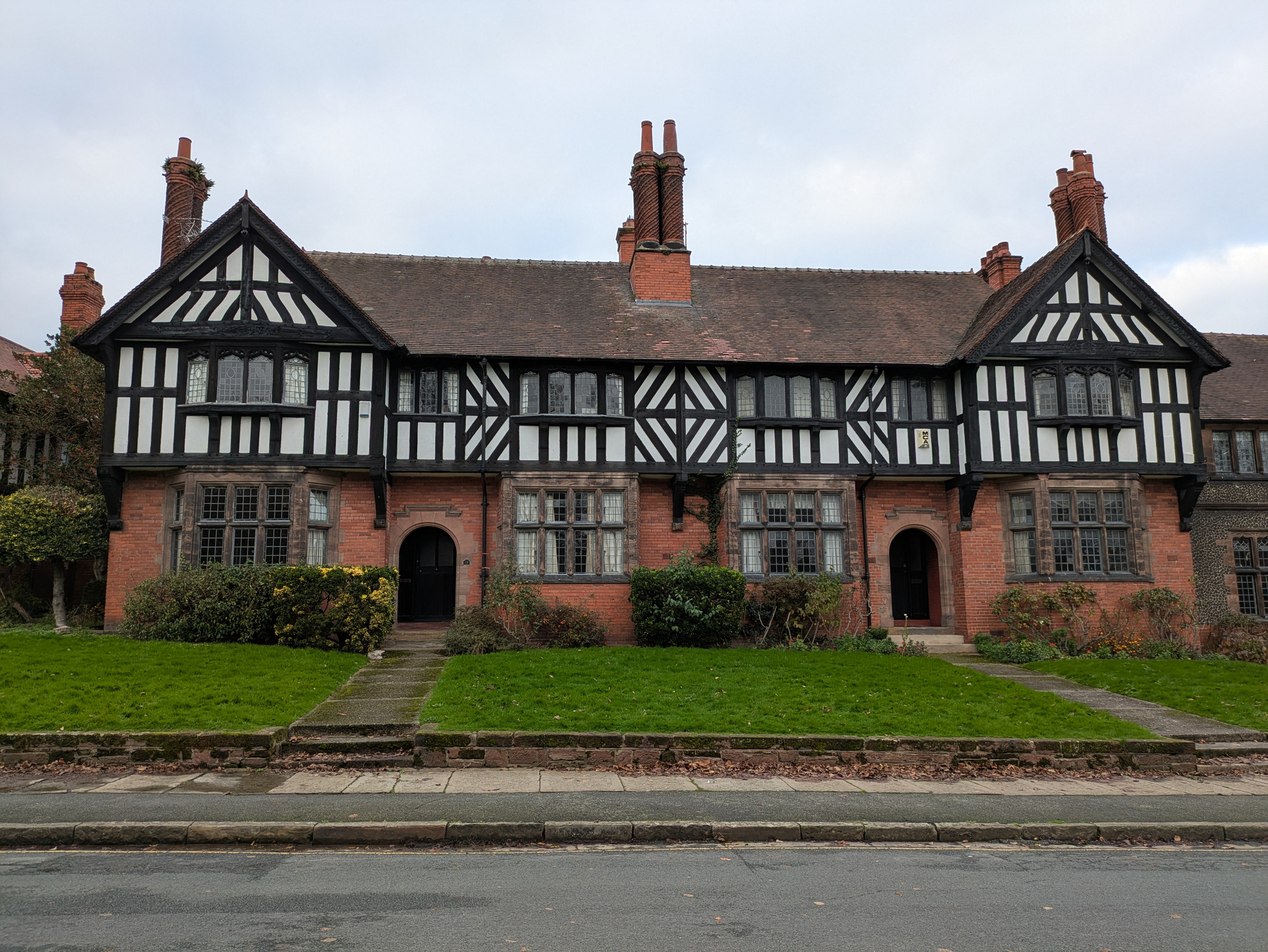 A faux Tudor-style building with distinctive black and white timber framing stands in front of a well-kept lawn.