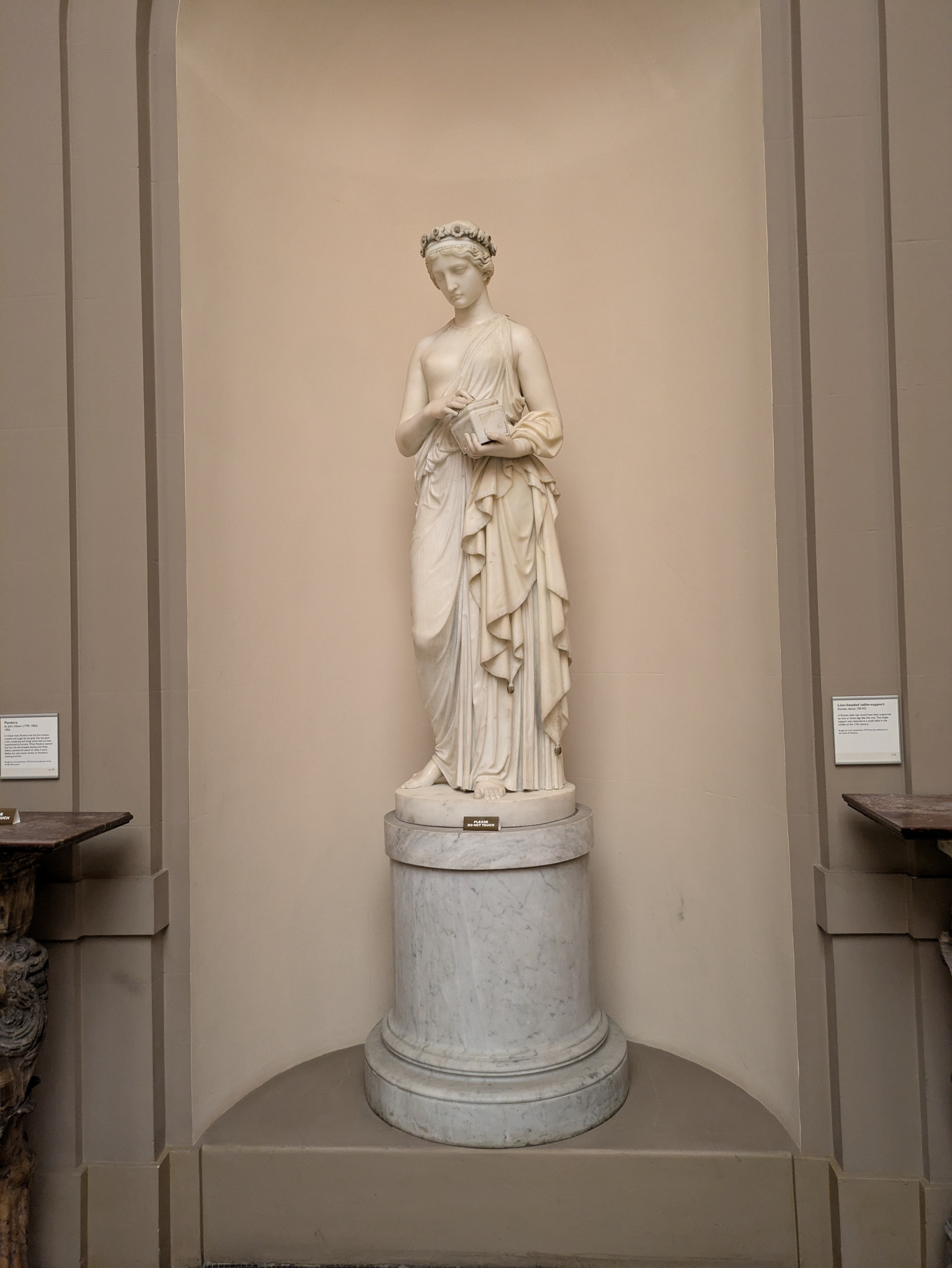 A marble statue of a classical woman stands gracefully on a pedestal in an alcove, draped in flowing attire.