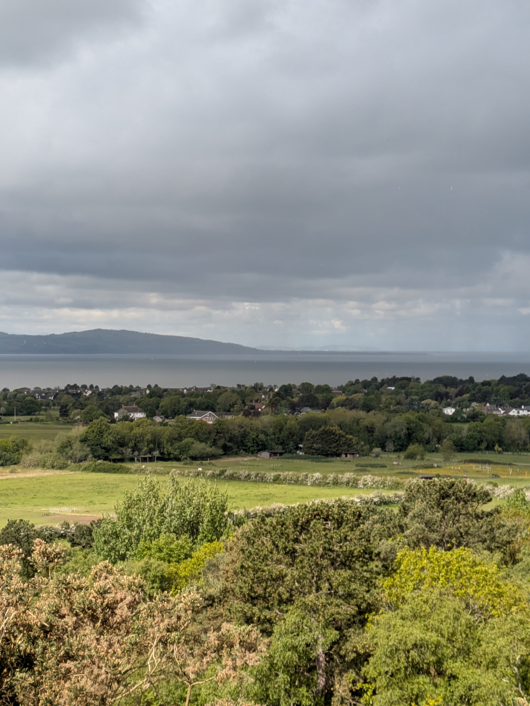 A scenic landscape features lush greenery, a coastline, and a cloudy sky.