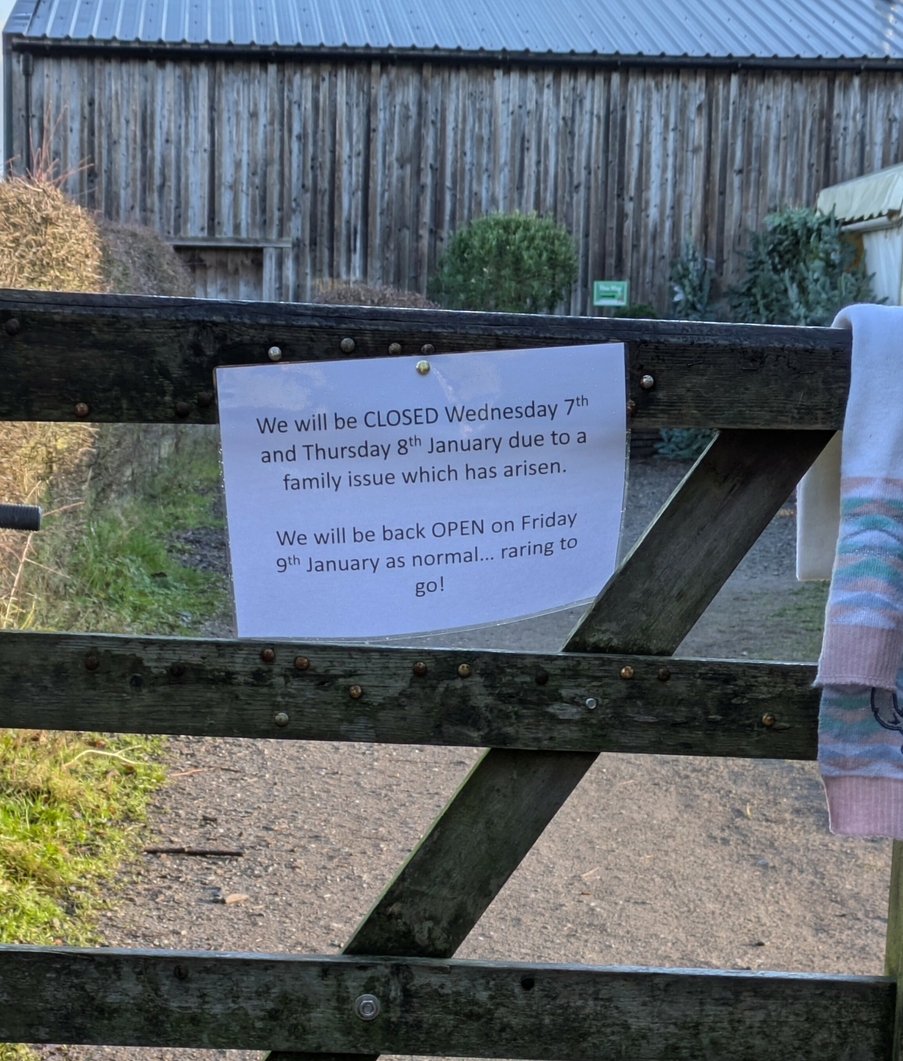 A wooden gate displays a sign announcing closure on January 7th and 8th due to a family issue, with a reopening on January 9th.