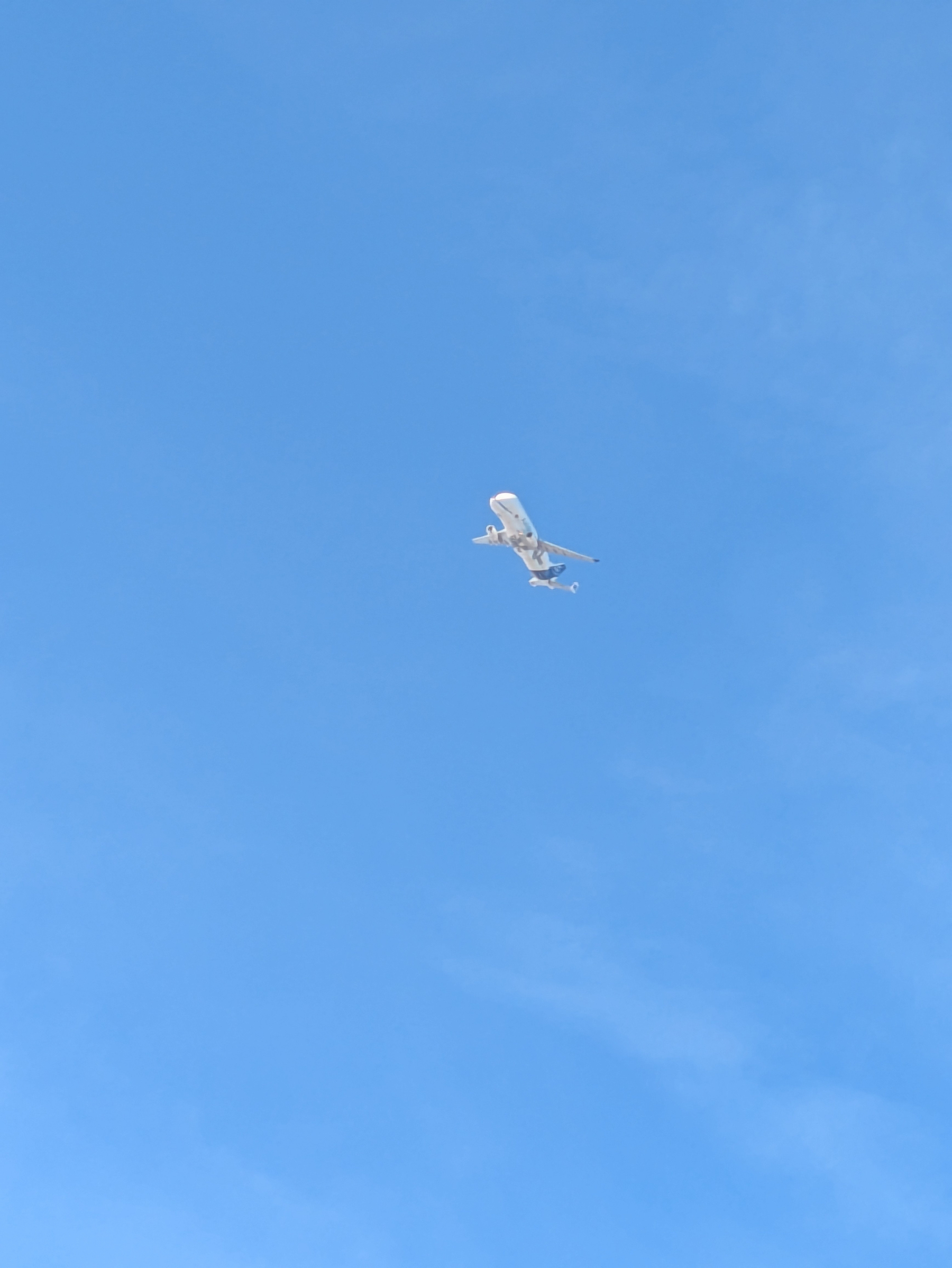 A plane is flying high against a clear blue sky.