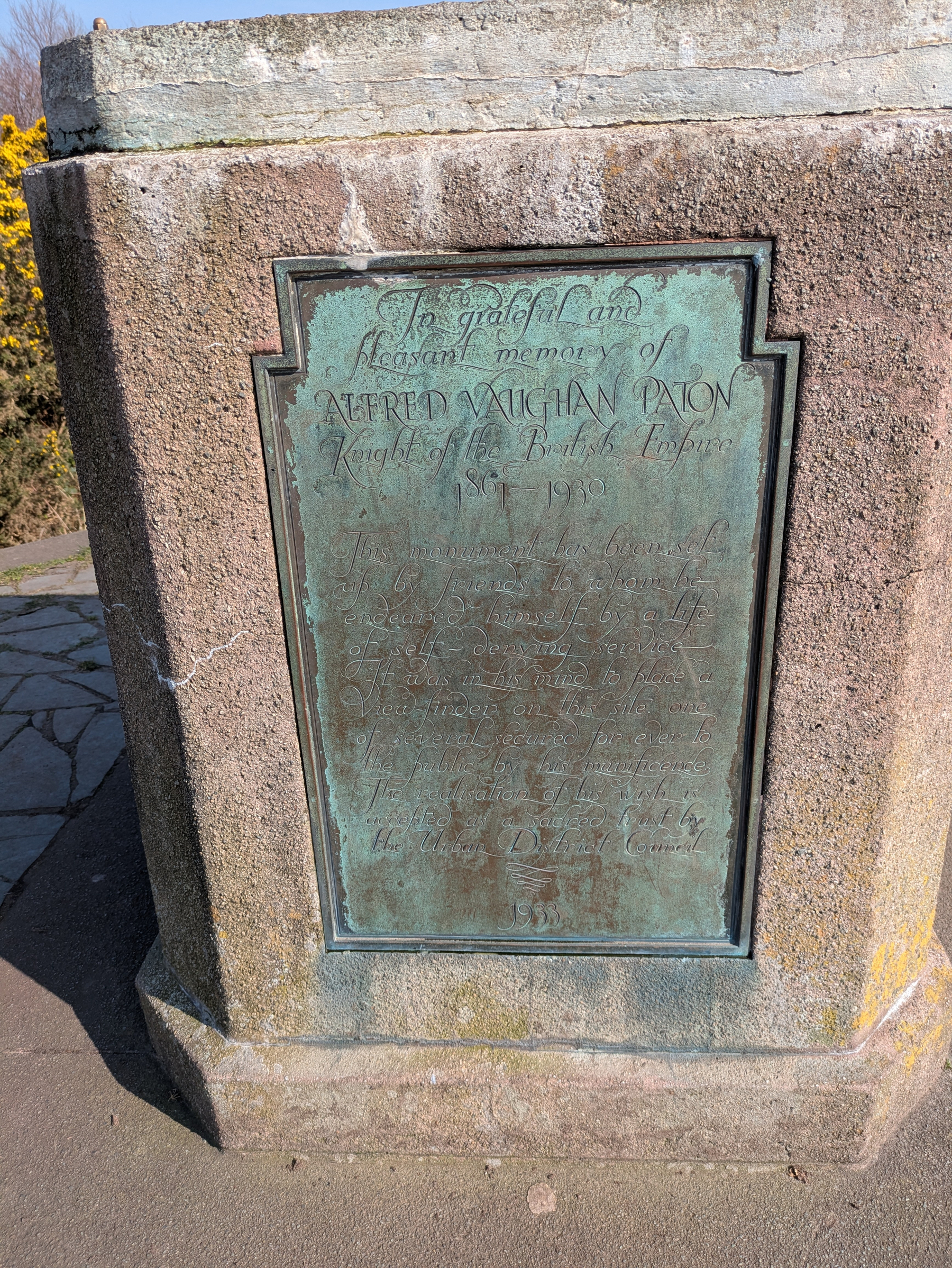 A weathered bronze plaque dedicated to Alfred Vaughan Paton, located on a stone monument.