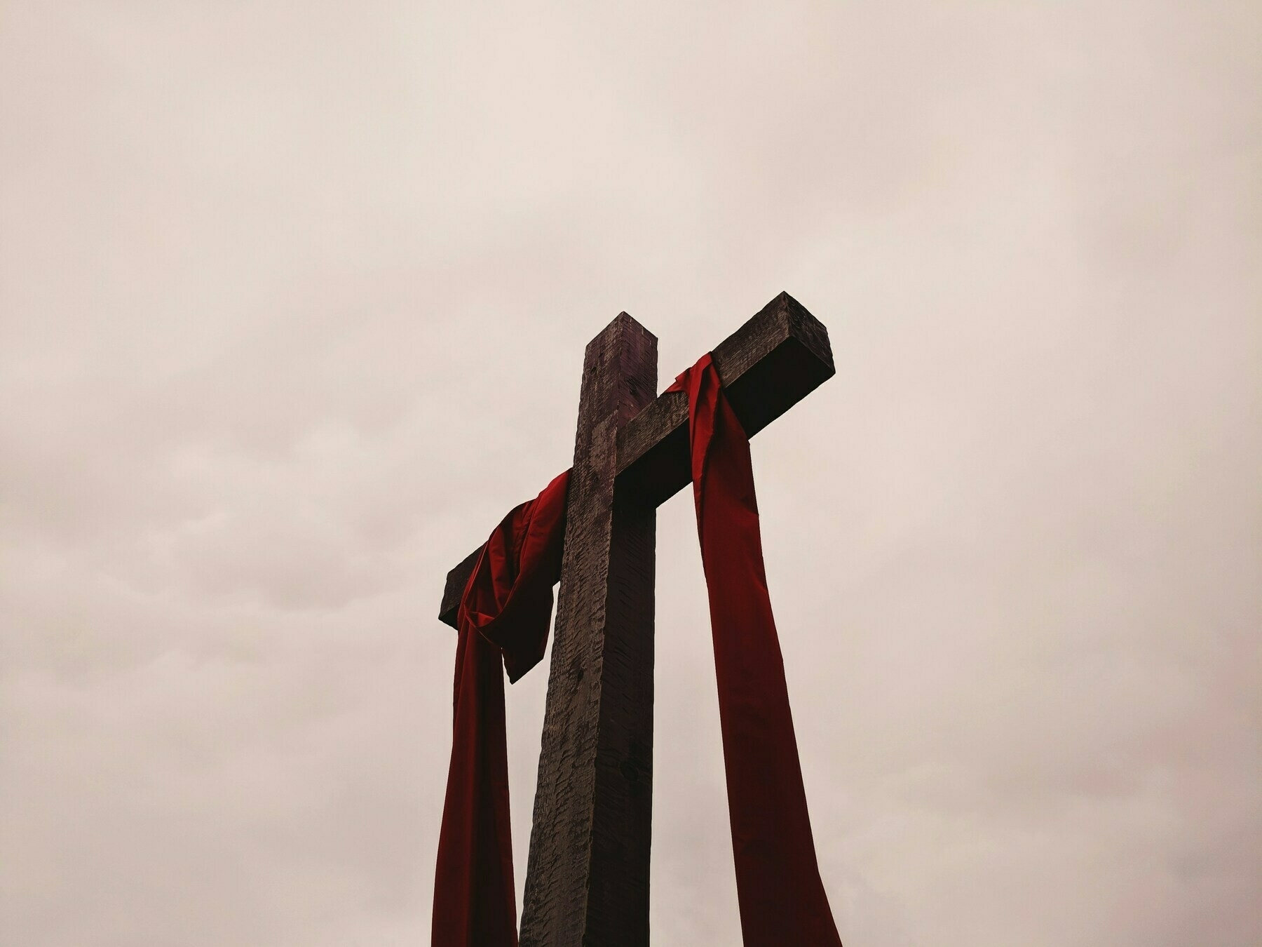 a cross draped with a purple sash against a cloudy sky