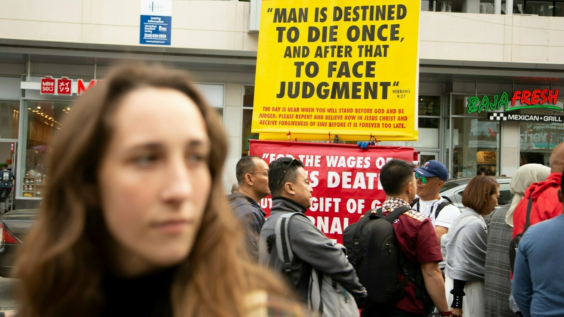 a woman in front of a sign that reads, 'man is destined to die once and then face judgement'