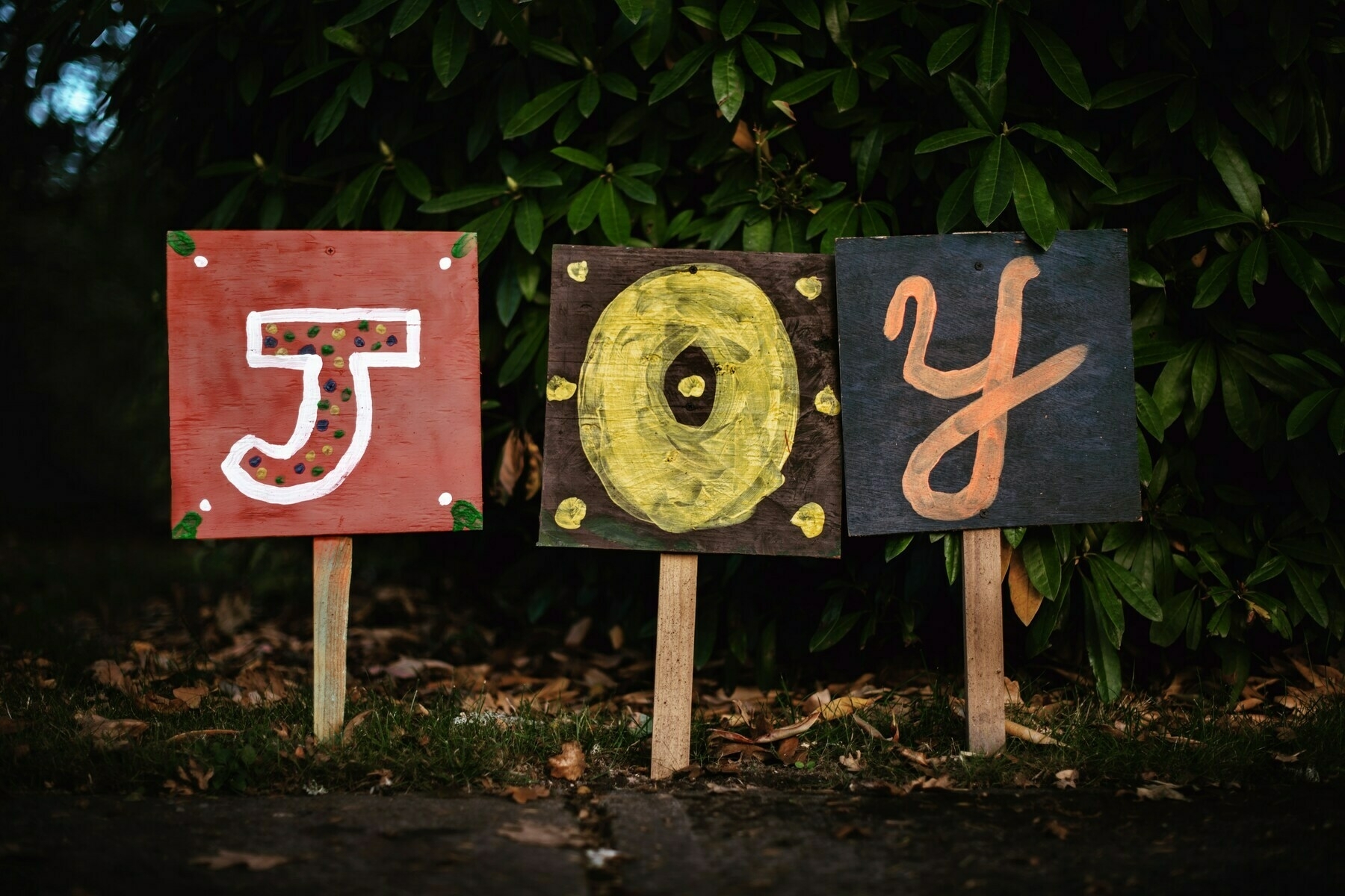 the word joy spelled out on colorful boards posted in a wooded setting