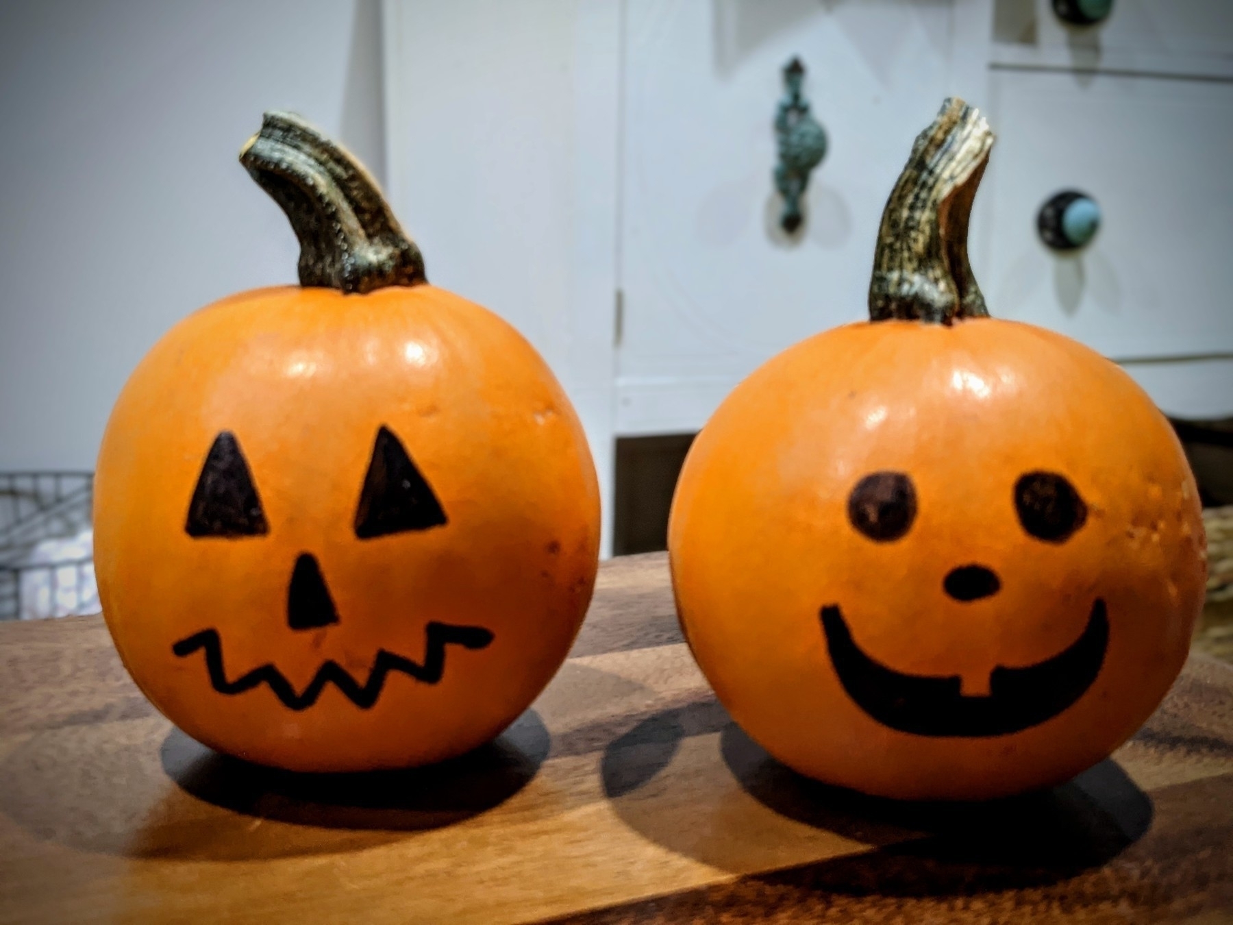 two tiny pumpkins with Jack-o'-lantern faces drawn on. 