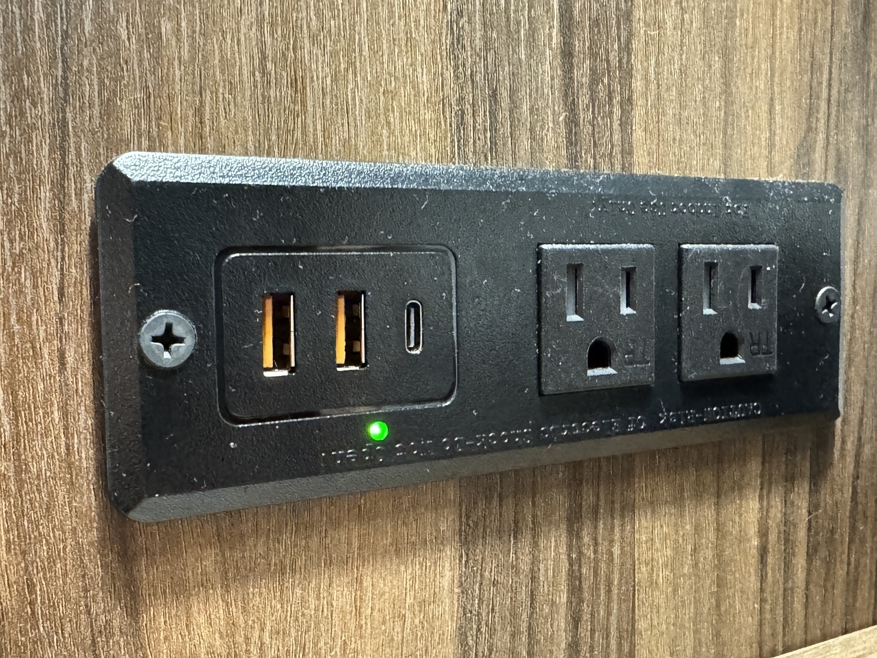A combination outlet in a hotel with 2 USB-A, one USB-C, and two standard US electrical sockets.
