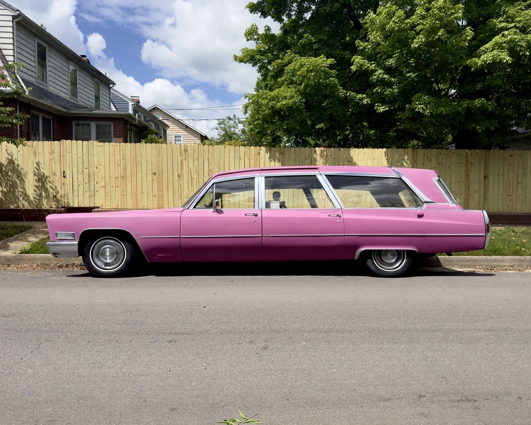 A pink Cadillac hearse with a fake skeleton in the back