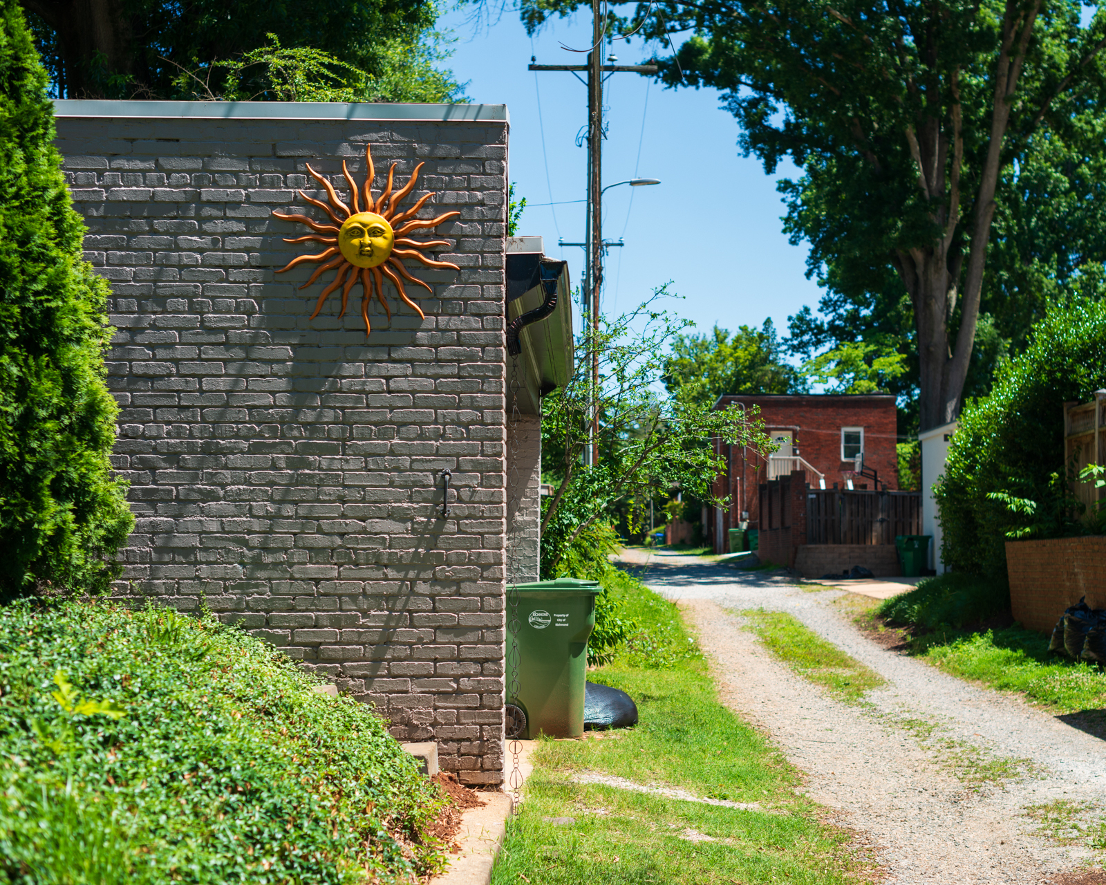 a sun relief sculpture on the side of a garage in an alleyway