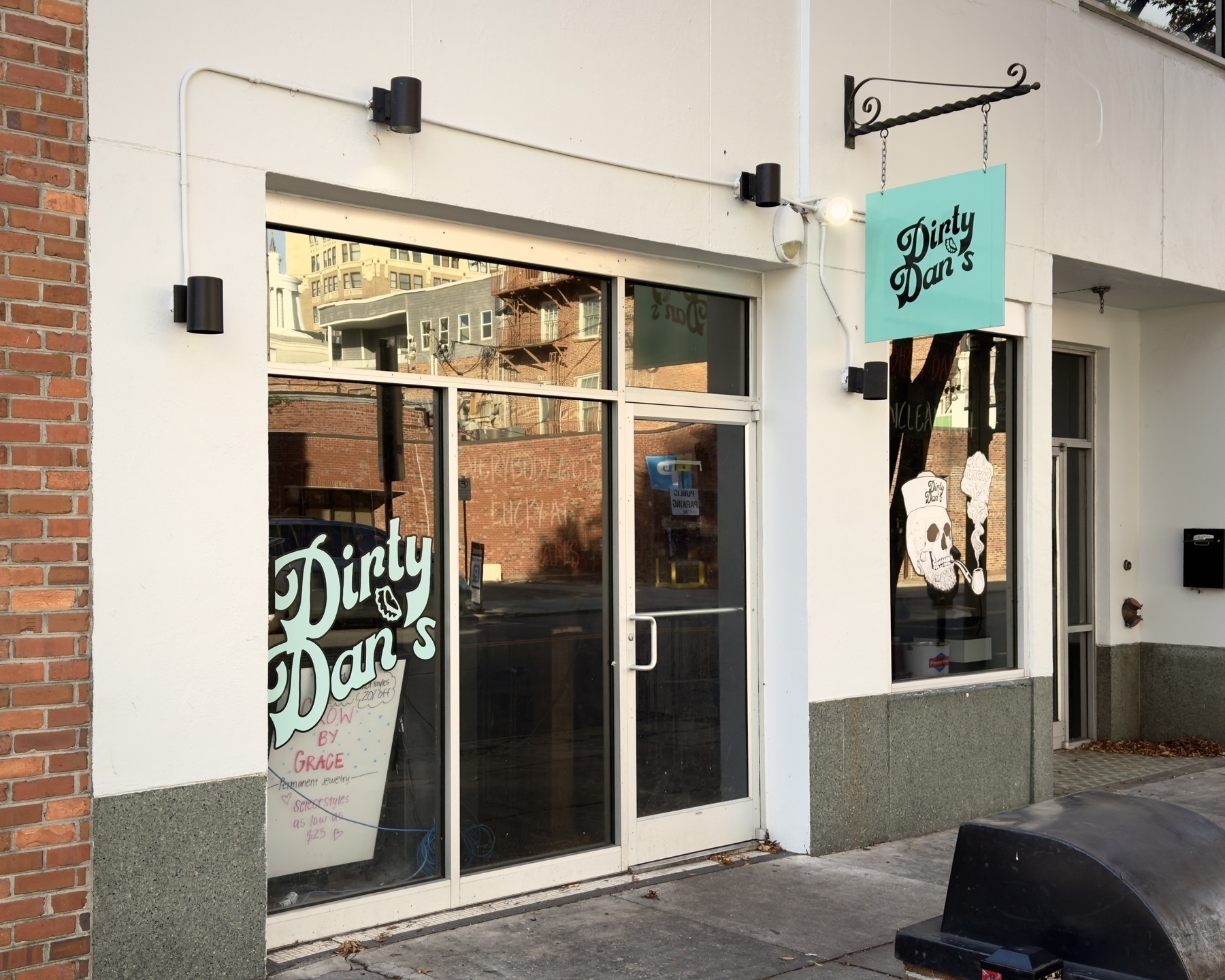 storefront for Dirty Dan's in Wilmington, NC with the name painted on the window and on a sign hanging beside the door