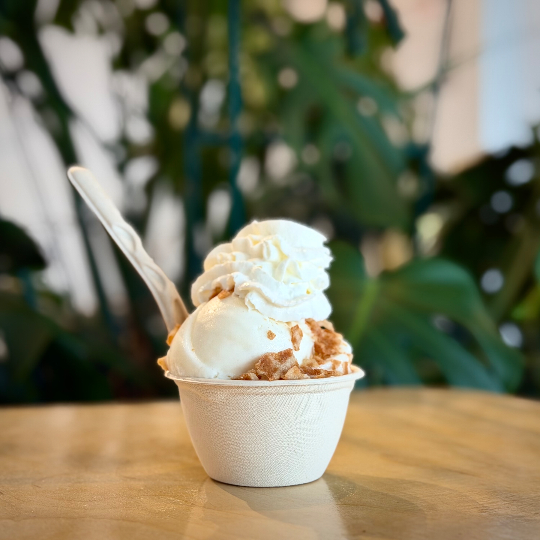 Pineapple sorbet with whipped cream and crushed cone pieces and a spoon sticking out