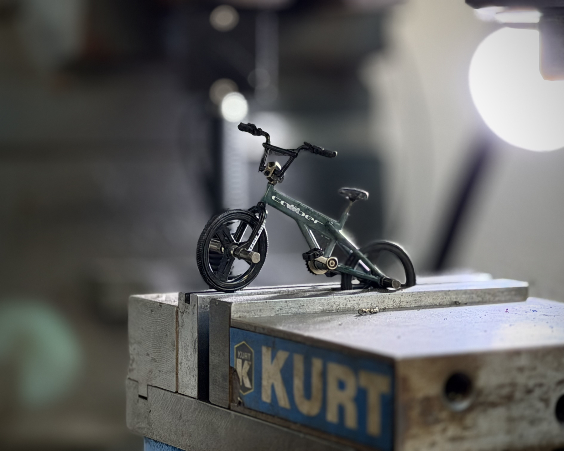 tiny toy bike clamped in a Kurt machinist vice on a milling machine