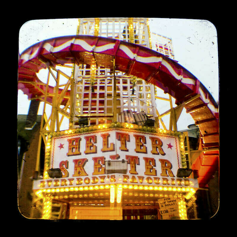 A photo of a helter skelter fairground ride framed by a round cornered, distorted dirty glass.