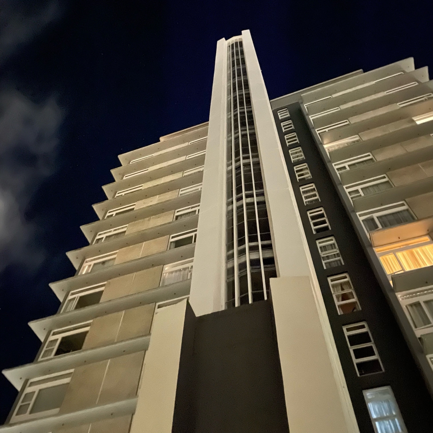 Nighttime view of a modernist tower block. 