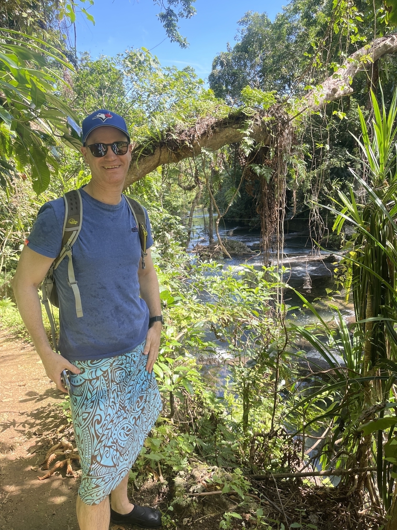 Standing on a lush river bank surrounded by rainforest - wearing a tshirt and sarong