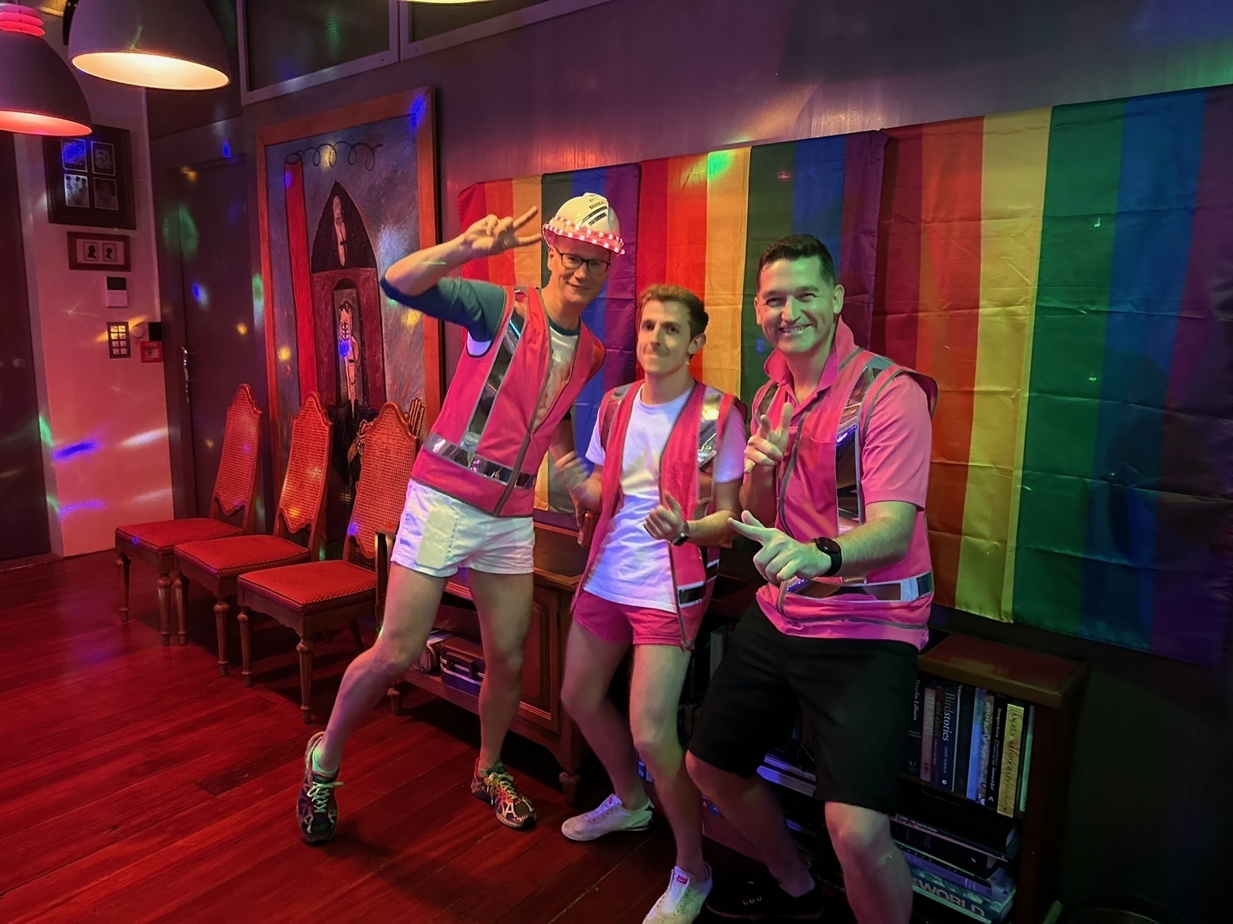 Three people in bright fluro tops with lights and rainbow flags 
