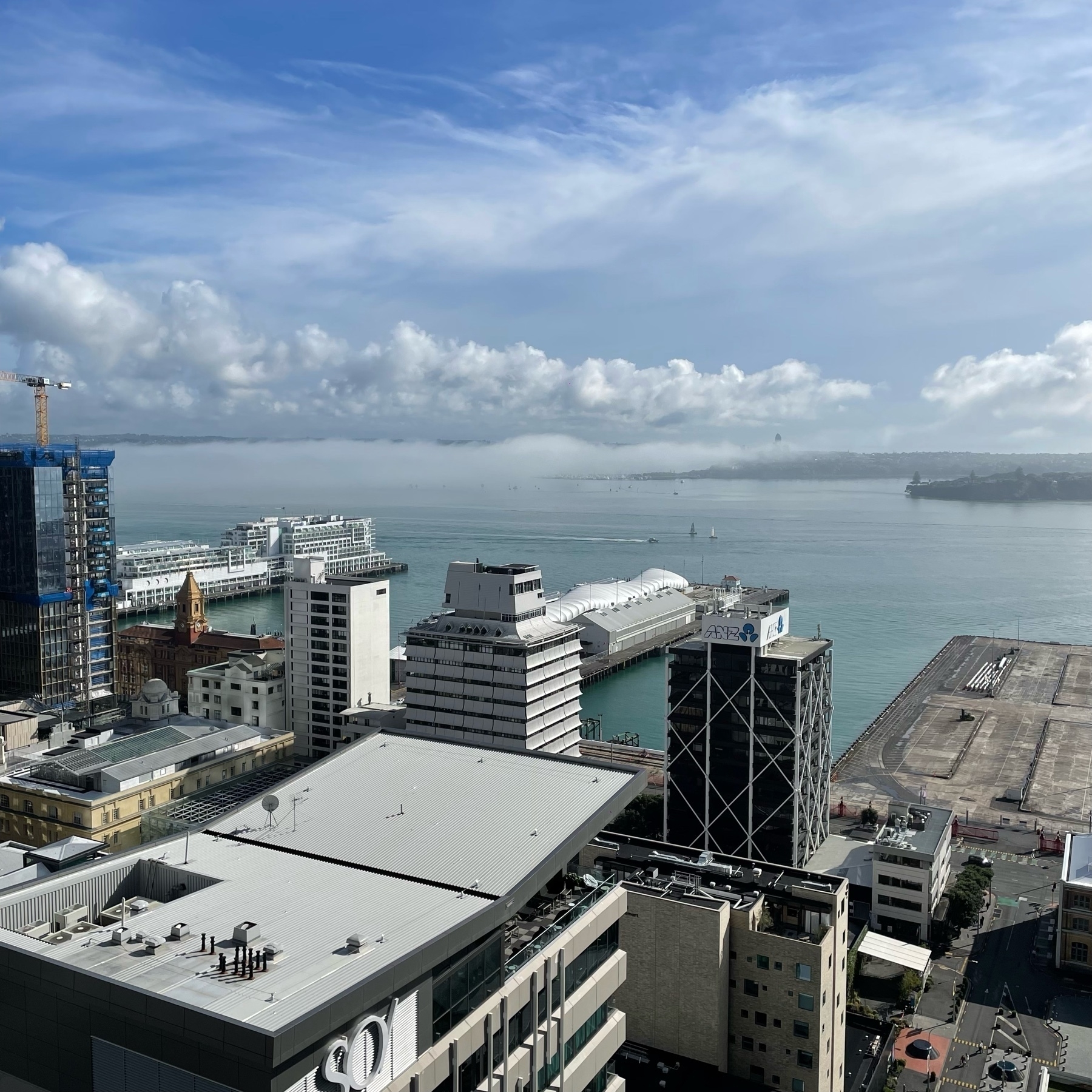 View across CBD buildings to a misty but otherwise sunny Auckland harbour 