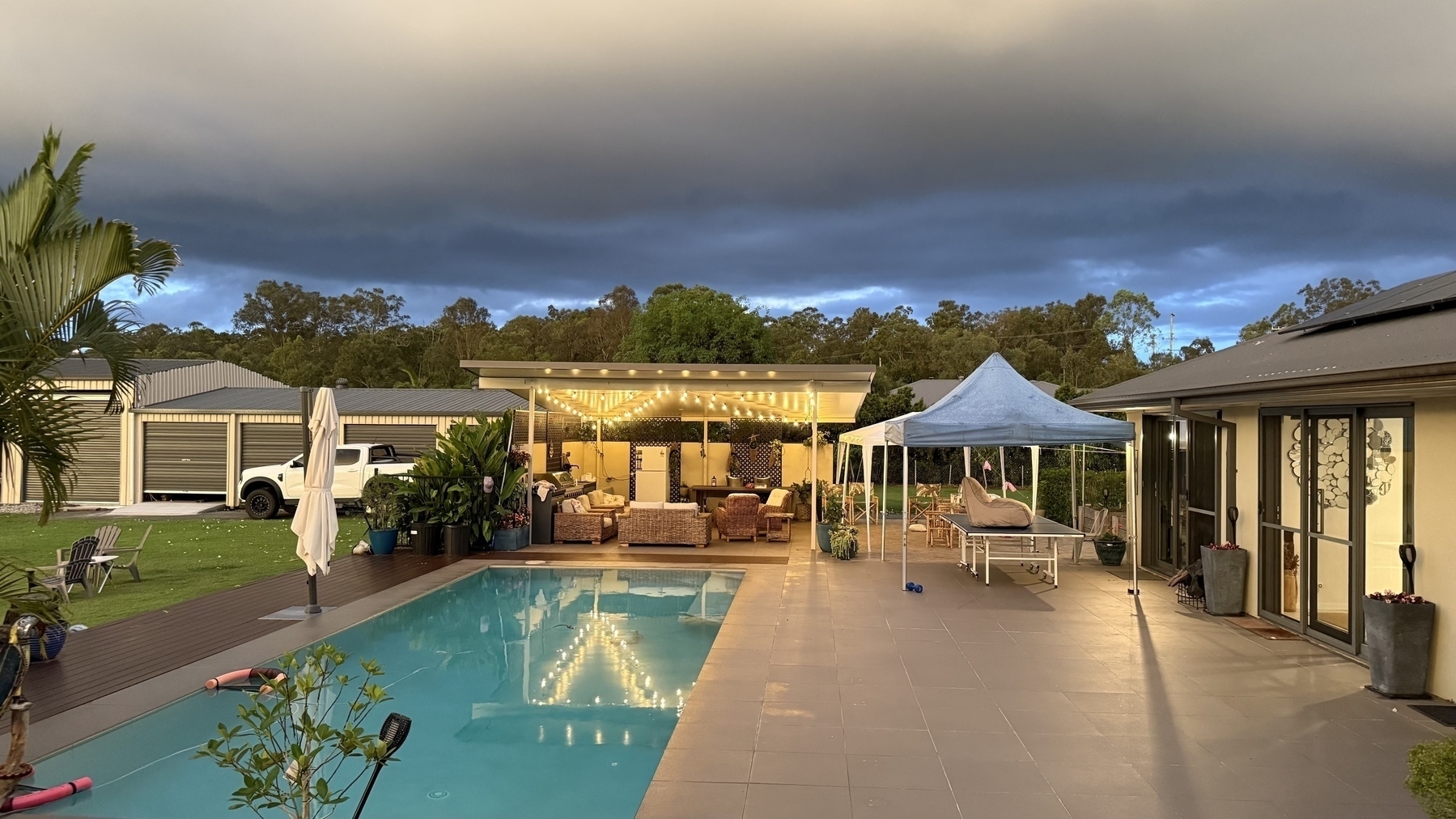 Thunderclouds over a pool and light filled cabana 