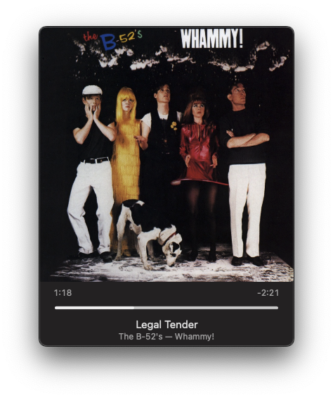 Five individuals in colorful attire pose with two dogs against a dark background on an album cover titled WHAMMY! by The B-52's.