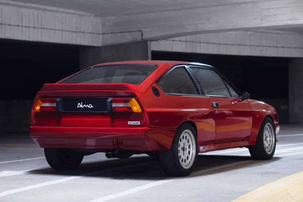 Auto-generated description: A red Alfa Romeo Sprint converted into an Alma Sprint 6C restomod sports car parked in a parking garage.