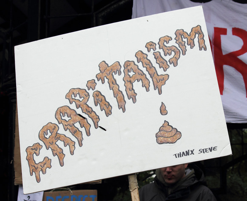 A protest sign spells CRAPITALISM in dripping letters, accompanied by a small drawing of excrement and the words THANX STEVE. From Occupy Toronto, 2011.