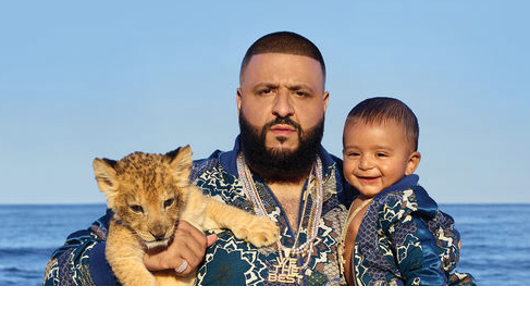DJ Khaled posing with a baby human and a baby lion