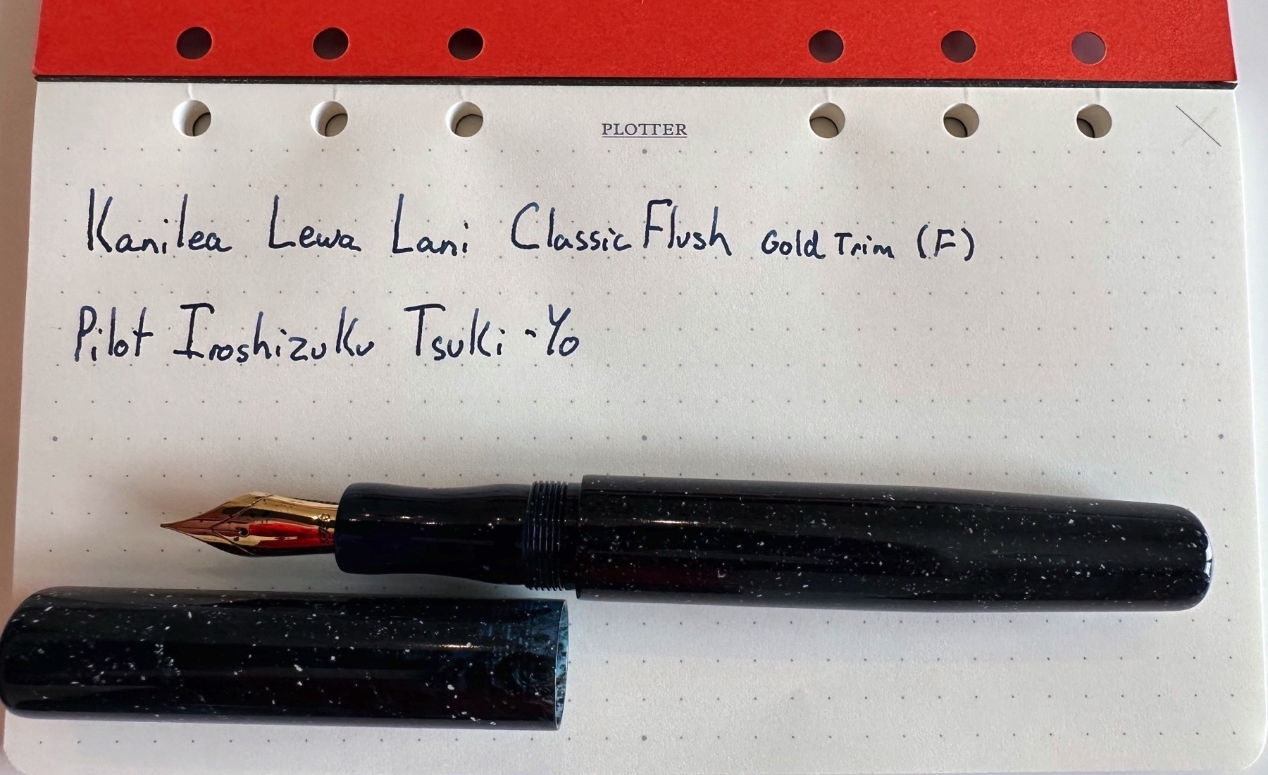 Kanilea Lewa Lani Fountain Pen laying over a sheet of paper that says “Kanliea Lewa Lani Classic Flush, Gold Trim (F), Pilot Iroshizuku Tsuki-yo.”