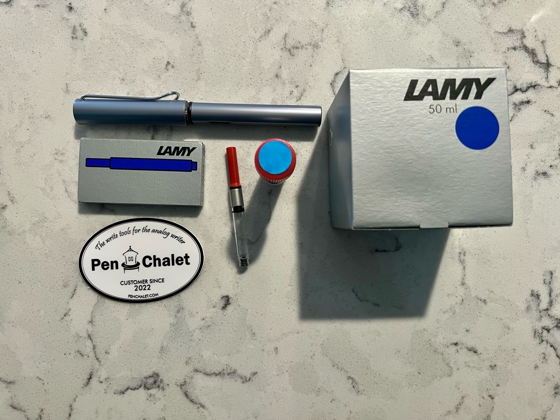 Photo of a Lamy AL-Star Fountain Pen, ink cartridges, and bottle of ink