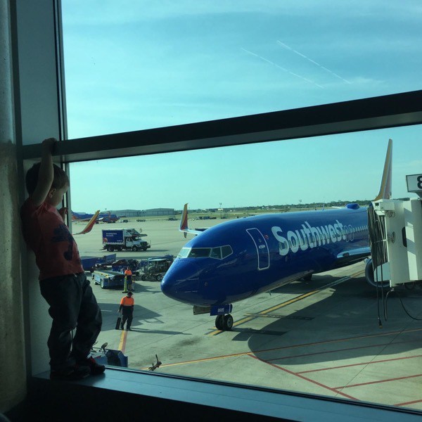 Boy stands in the window by an airplane at an airport gate