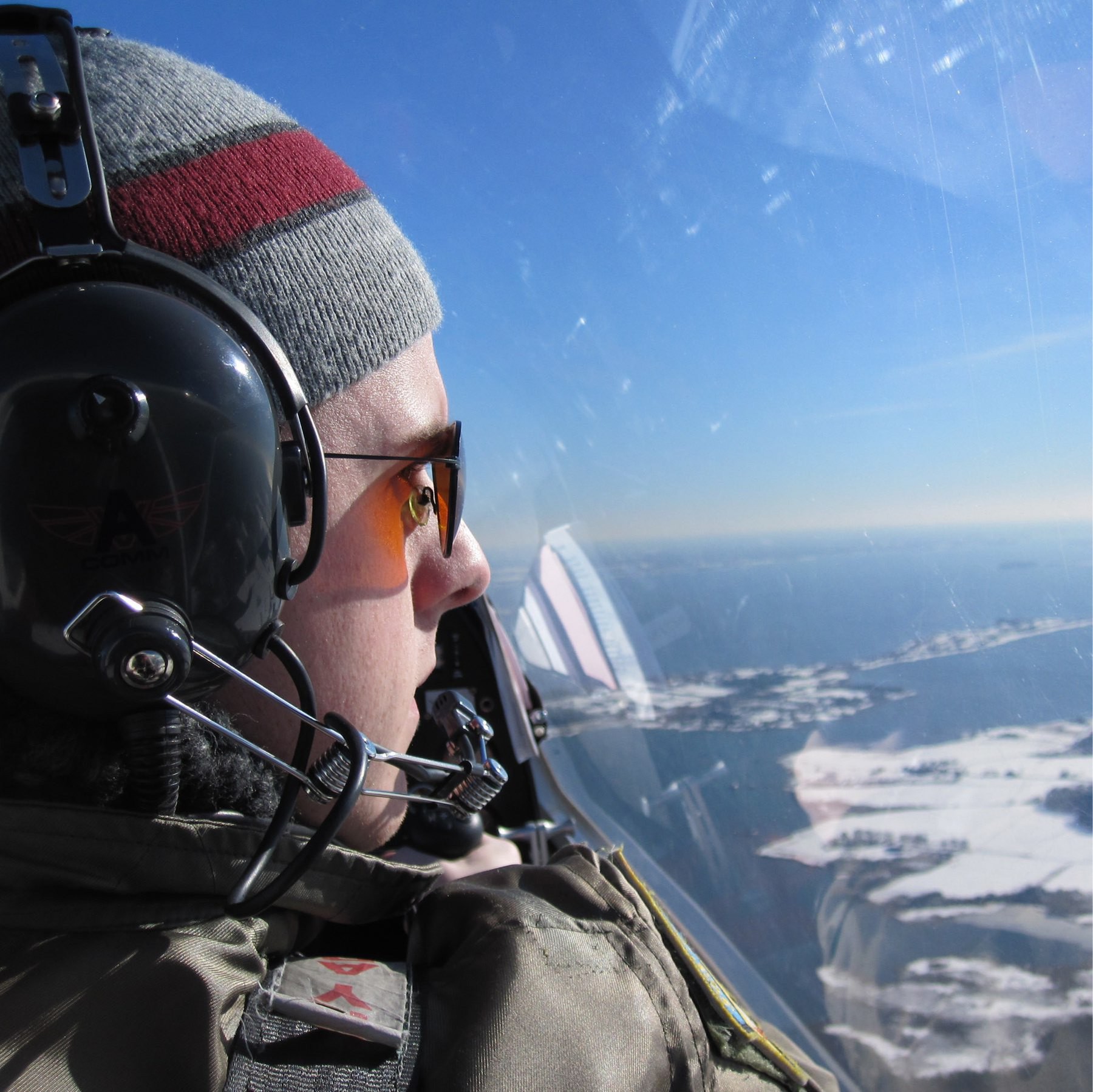 Chet flying an airplane over snow-covered terrain.