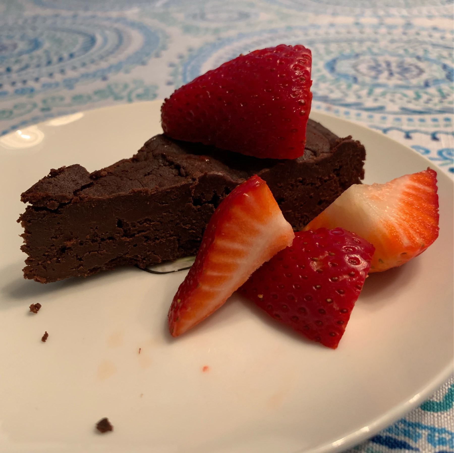 Slice of chocolate torte on a plate, garnished with strawberry quarters