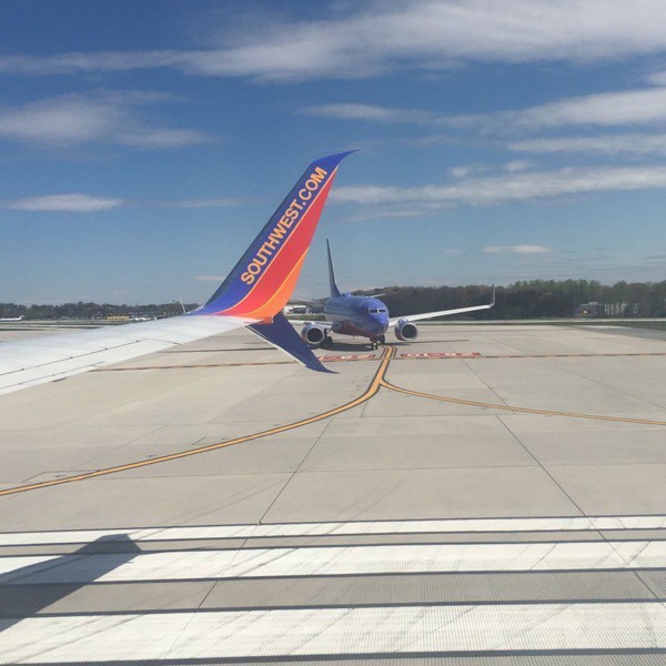 Southwest airline holds short of the runway, with a Boeing 737 wing in view