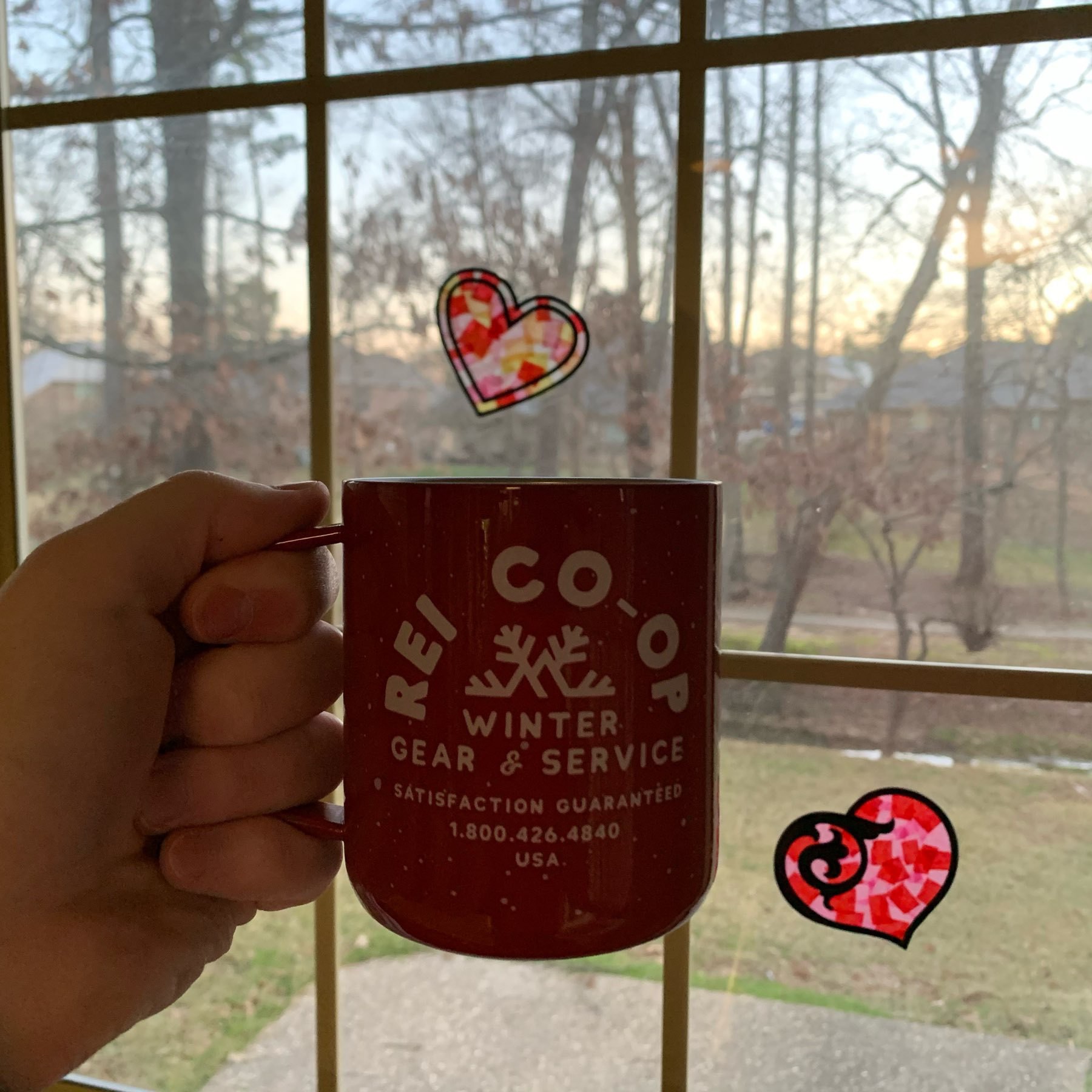 Coffee mug with hearts against a sunrise backdrop. 